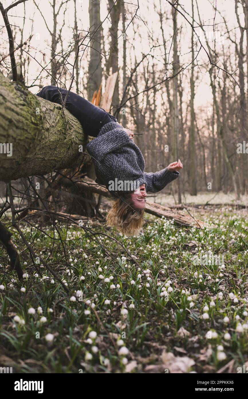 Laughing woman hanging on fallen tree scenic photography Stock Photo