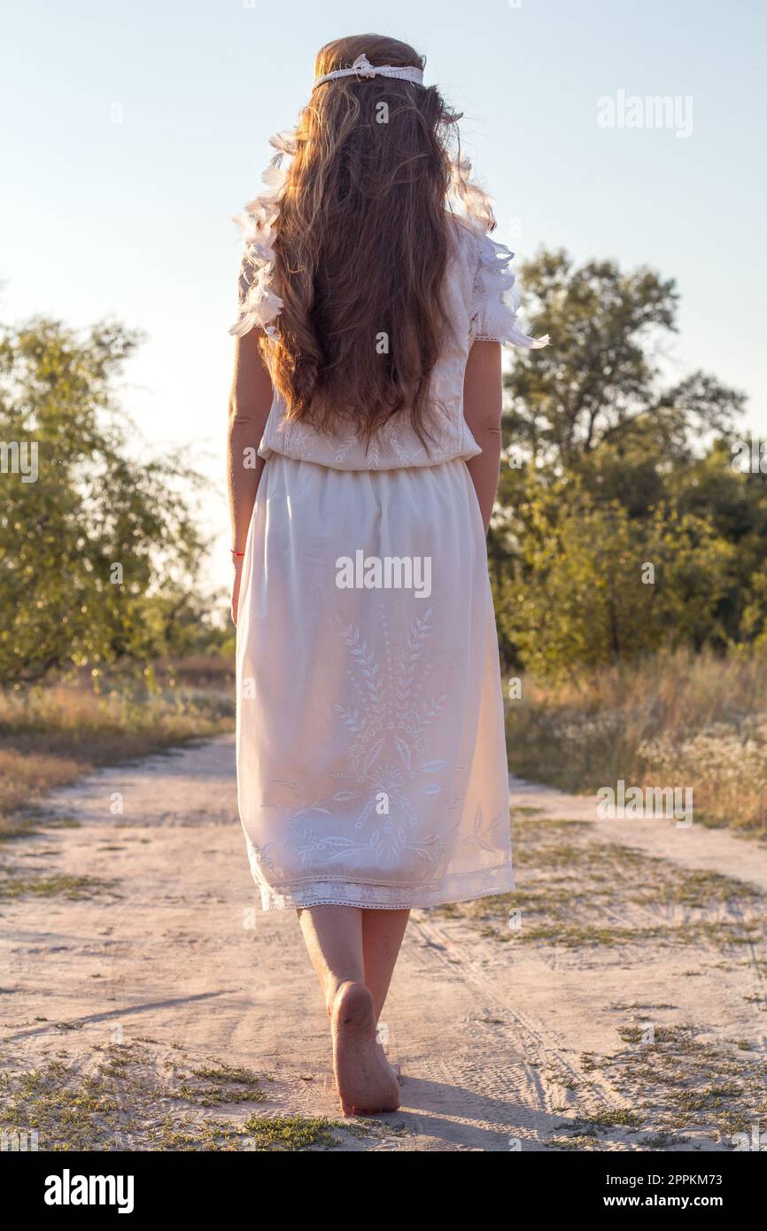 Close up beautiful barefoot woman in white dress strolling concept photo Stock Photo