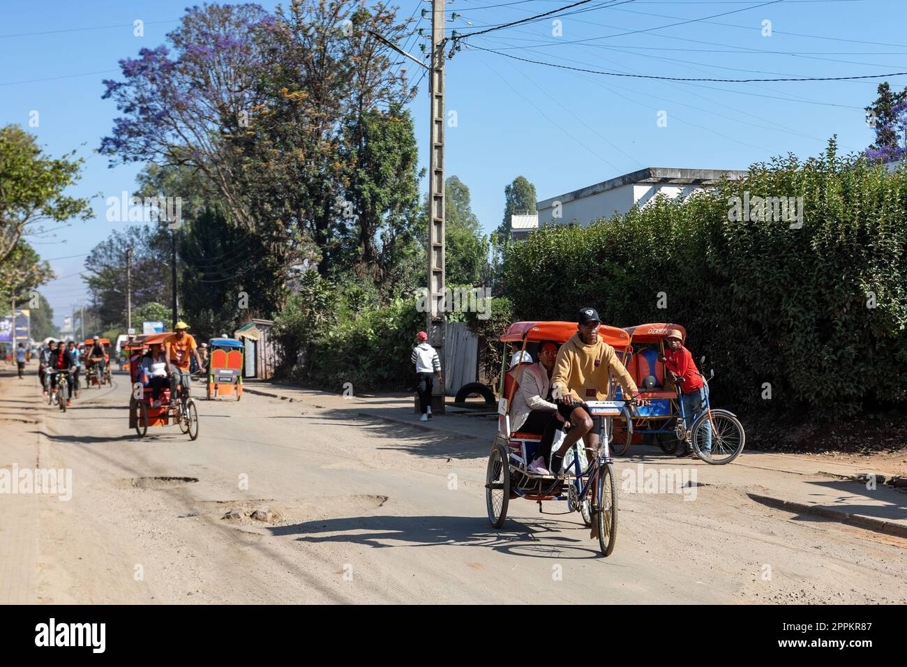 Traditional rickshaw bicycle with Malagasy people on the street of Antsirabe, one of the ways to earn money. Everyday life on the street of Madagascar. Stock Photo