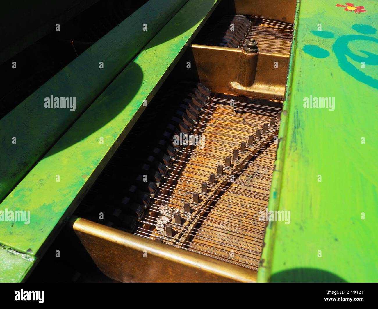 Strings, soundboard and piano mechanics. Piano on the street. Piano painted green. Performance of a piece of music. Street concert on a summer sunny day. Stock Photo