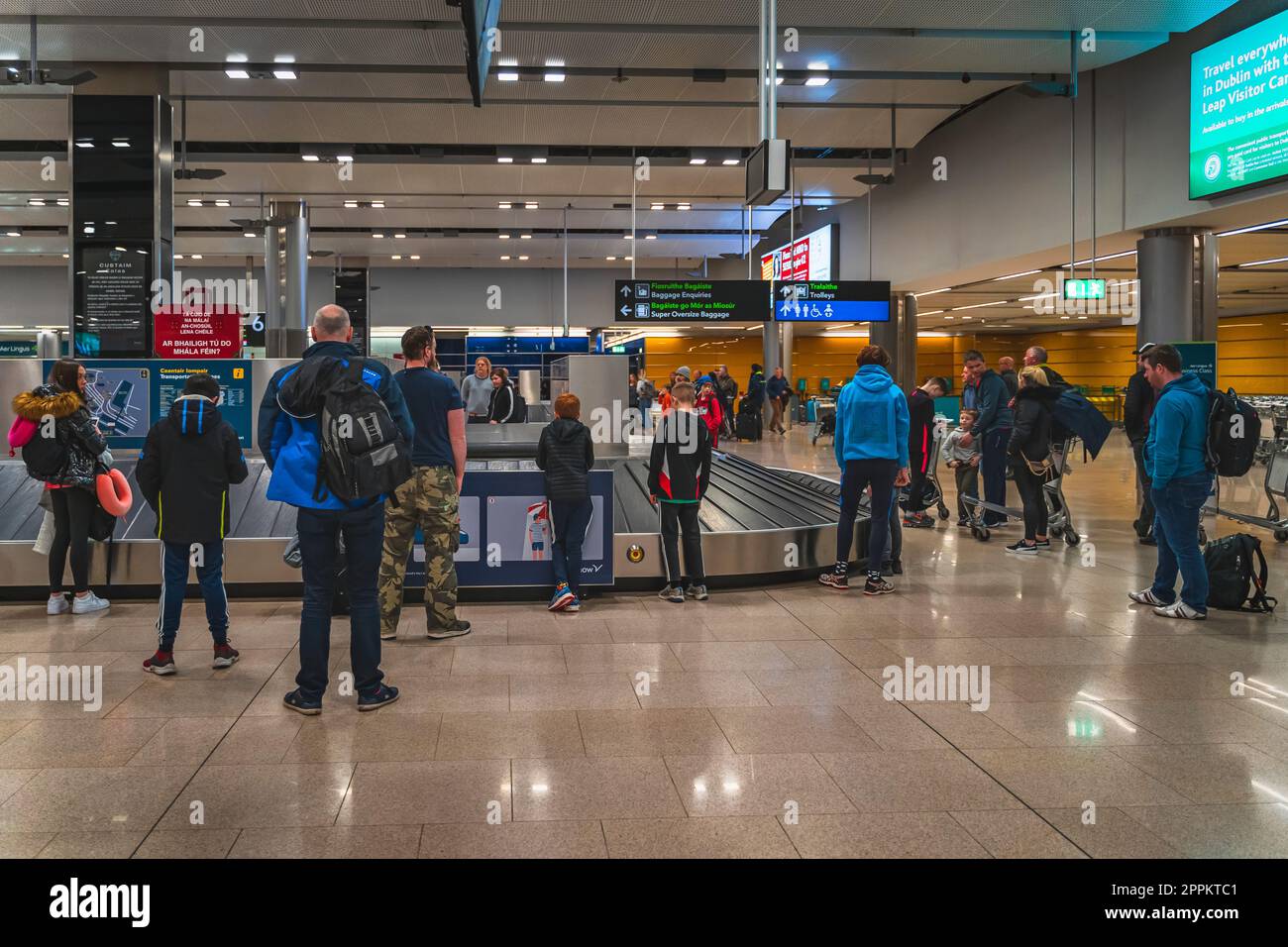 People waiting at belt conveyor to collect luggage after arrival to Dublin airport Stock Photo