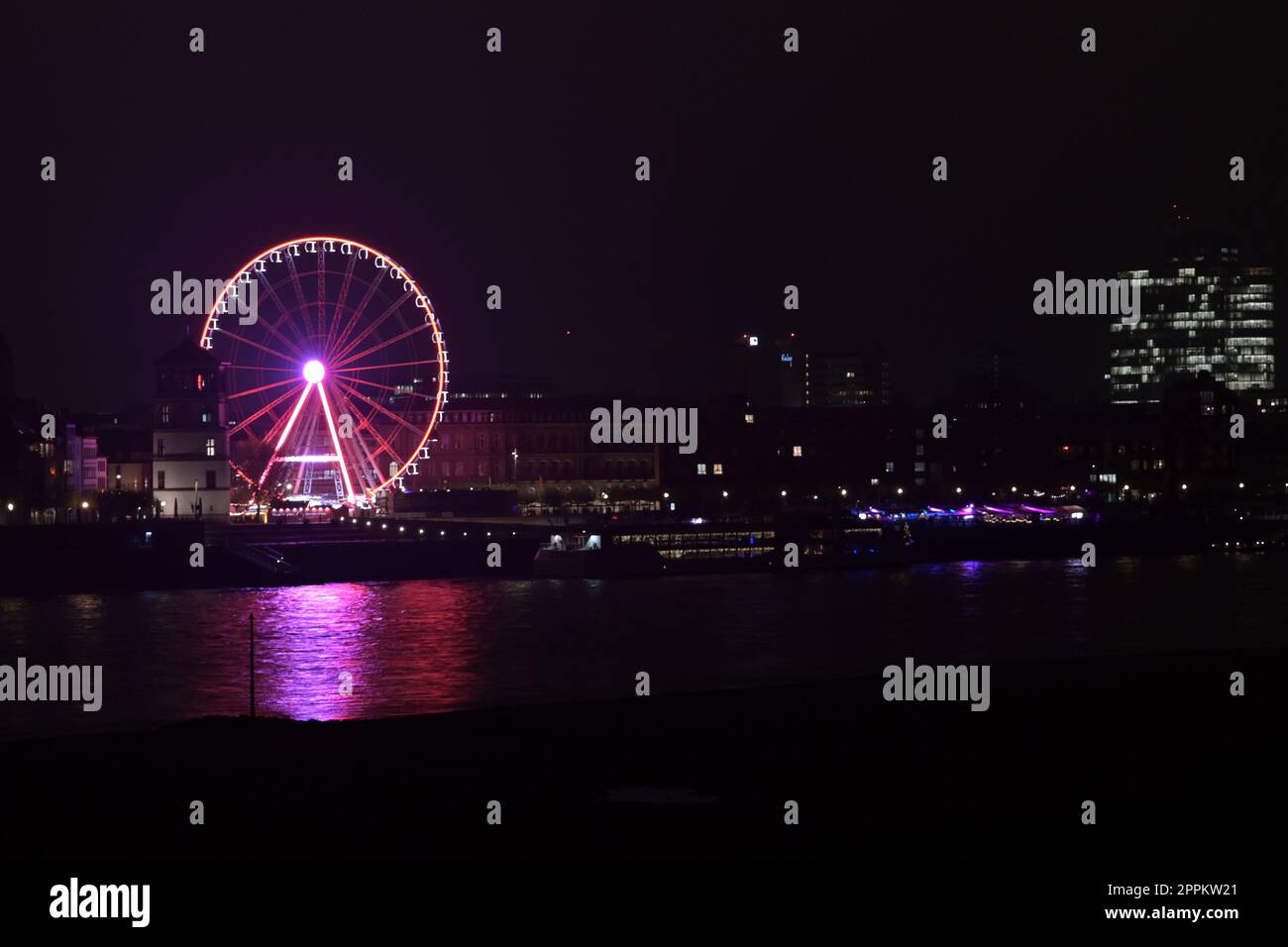 Rhine riverbank by night with castle tower and Ferris pink wheel in Duesseldorf, Germany Stock Photo