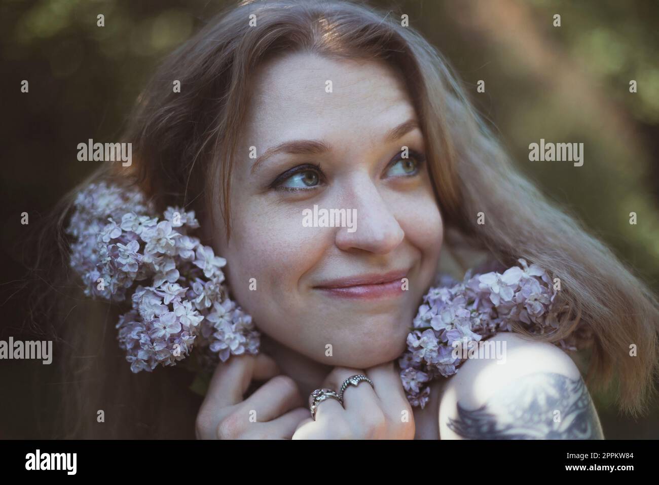 Close up happy woman pressing lilac stems to face portrait picture Stock Photo