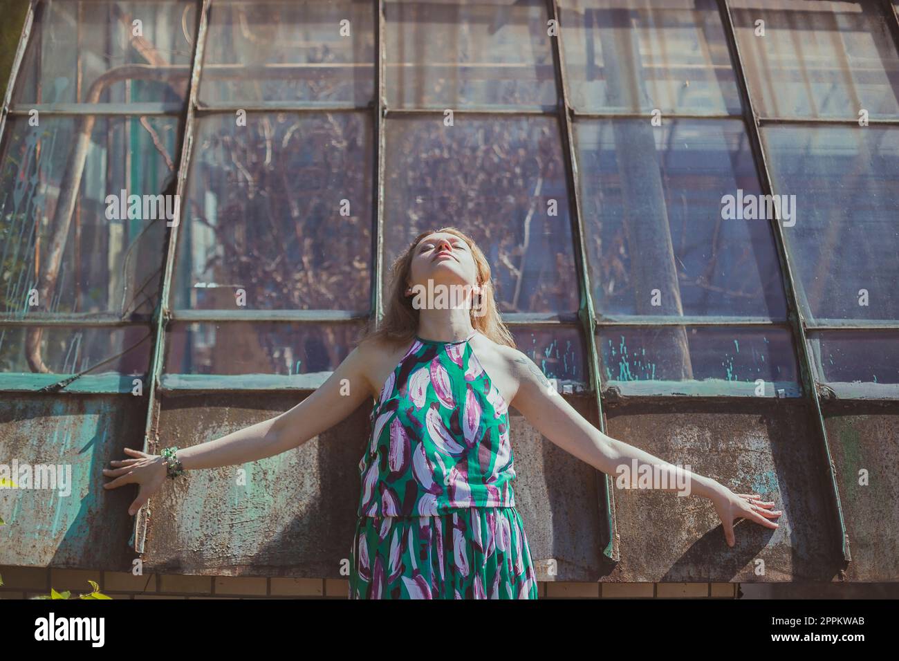 Young woman with closed eyes posing against tall windows scenic photography Stock Photo
