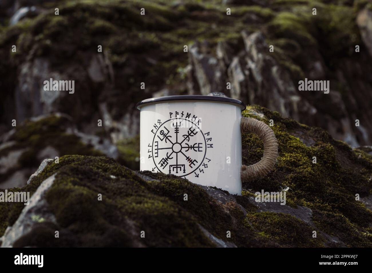 Close up enamel mug with runes on rock concept photo Stock Photo