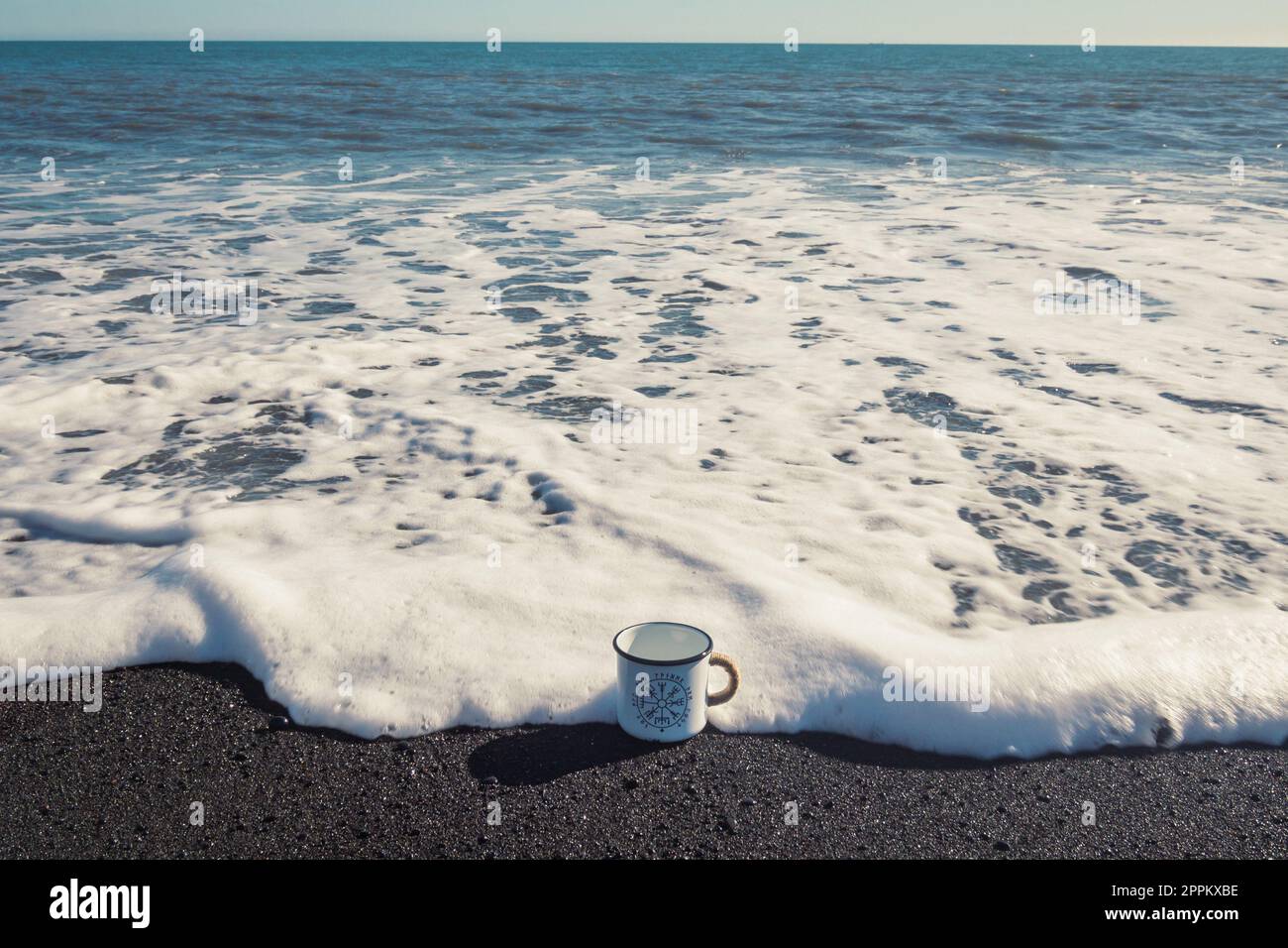 Close up enamel cup on sea surfline concept photo Stock Photo