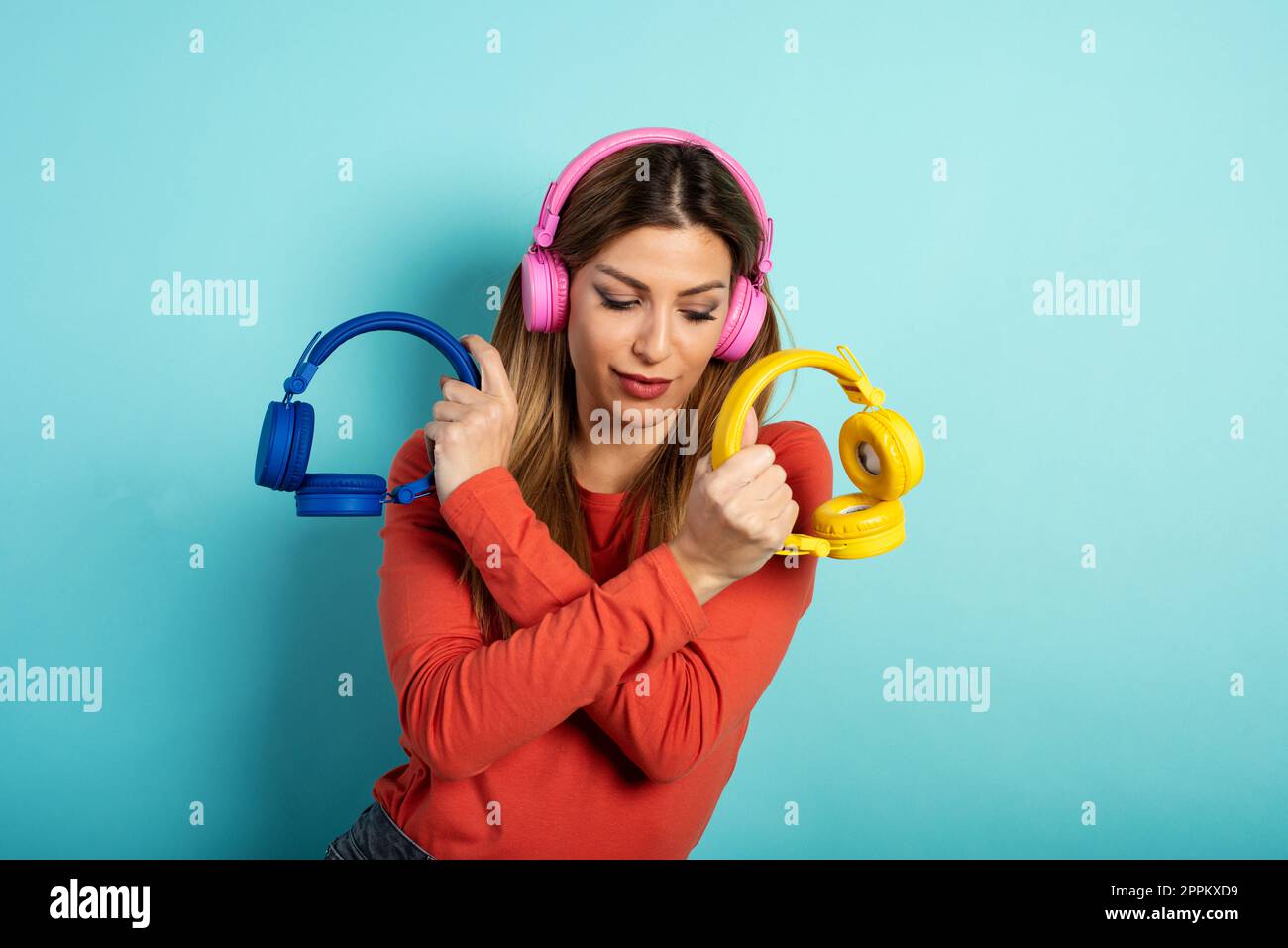 Girl with headset listens to music and dances. emotional and energetic expression. Cyan background Stock Photo