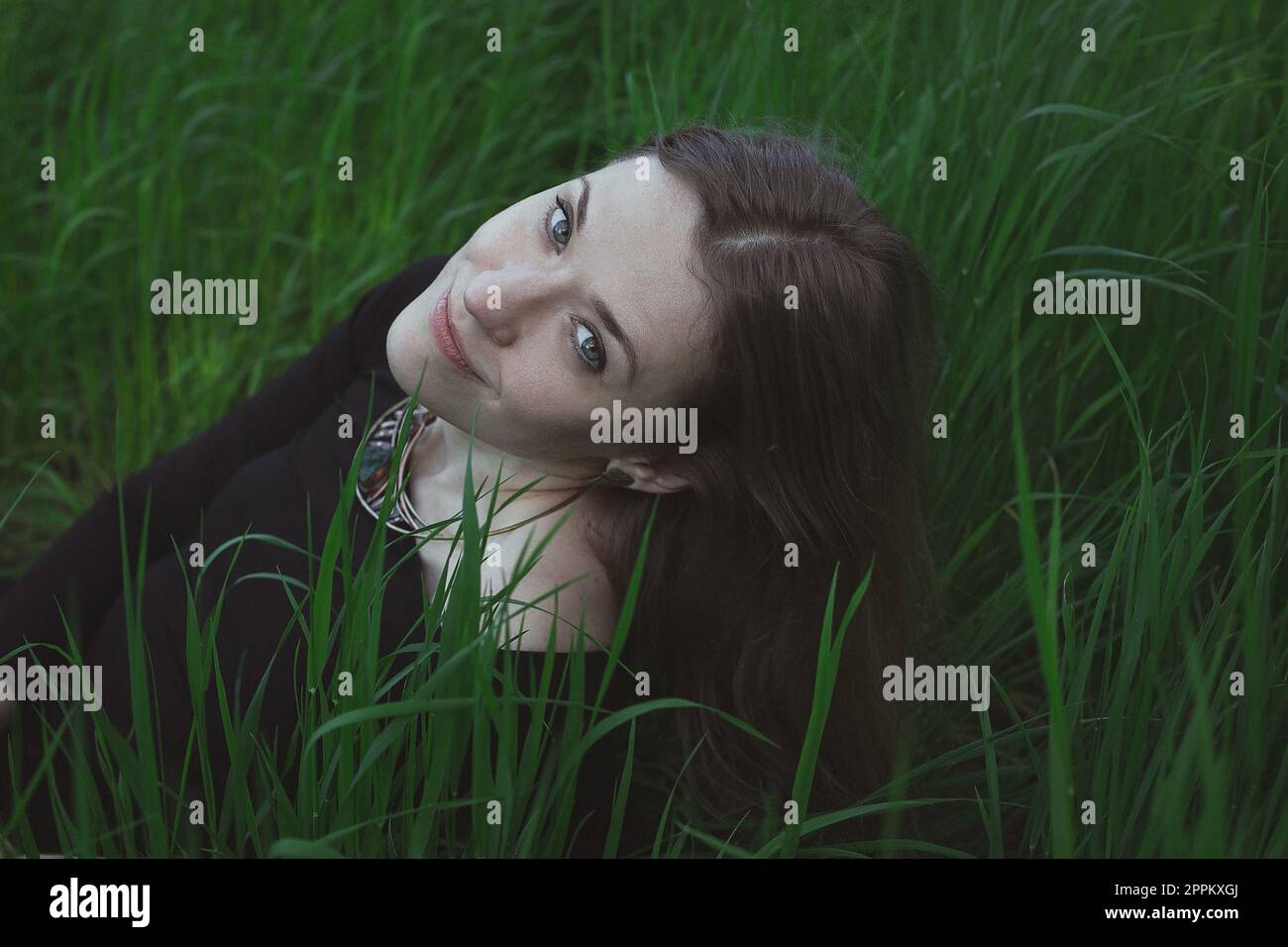 Close up smirking woman in tall grass staring directly into camera portrait picture Stock Photo