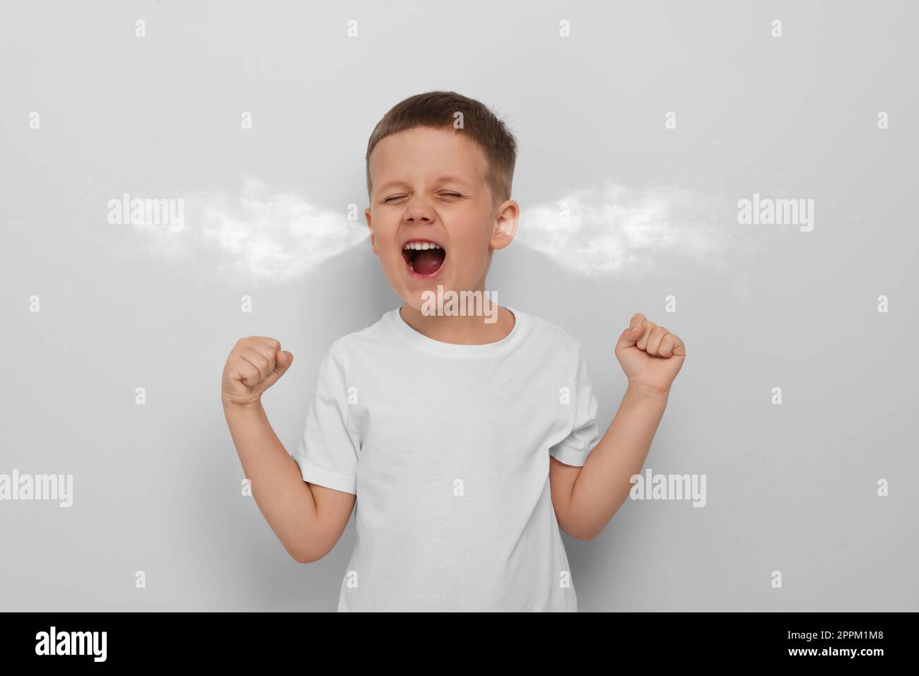 Aggressive little boy with steam coming out of his ears on grey background Stock Photo