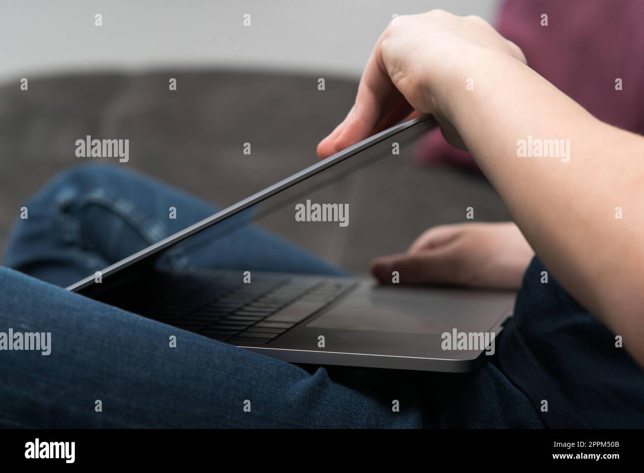 Digital laptop computer in male hands, side view closeup. Young business man close gray metal lid of portable notebook. Stock Photo