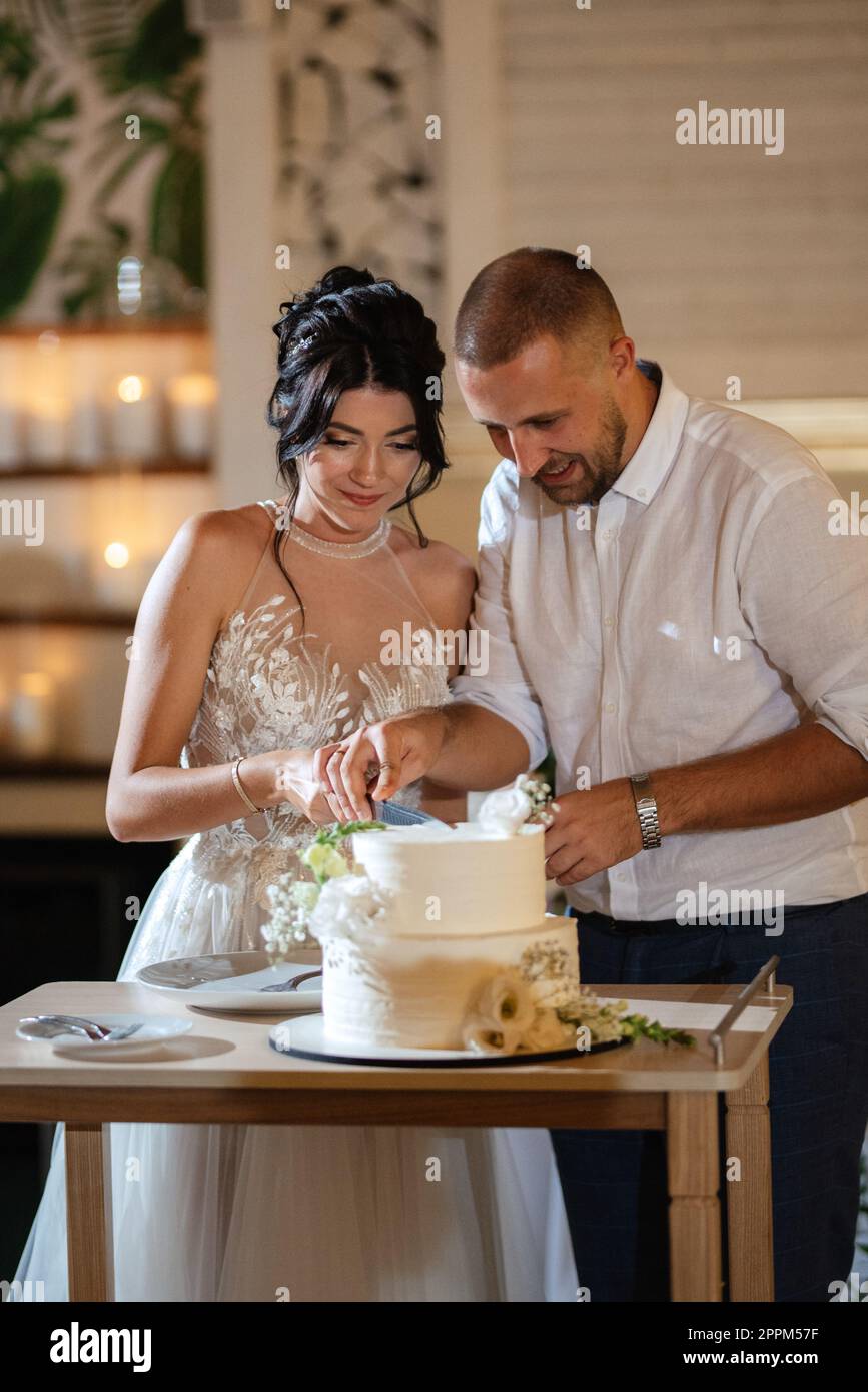 newlyweds happily cut and taste the wedding cake Stock Photo