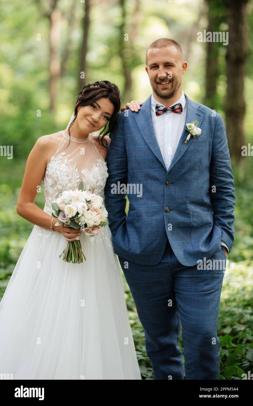 wedding walk of the bride and groom in the deciduous forest in summer ...