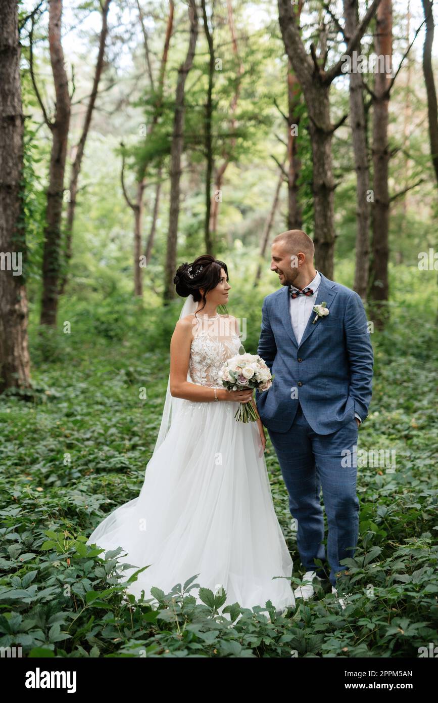 wedding walk of the bride and groom in the deciduous forest in summer ...