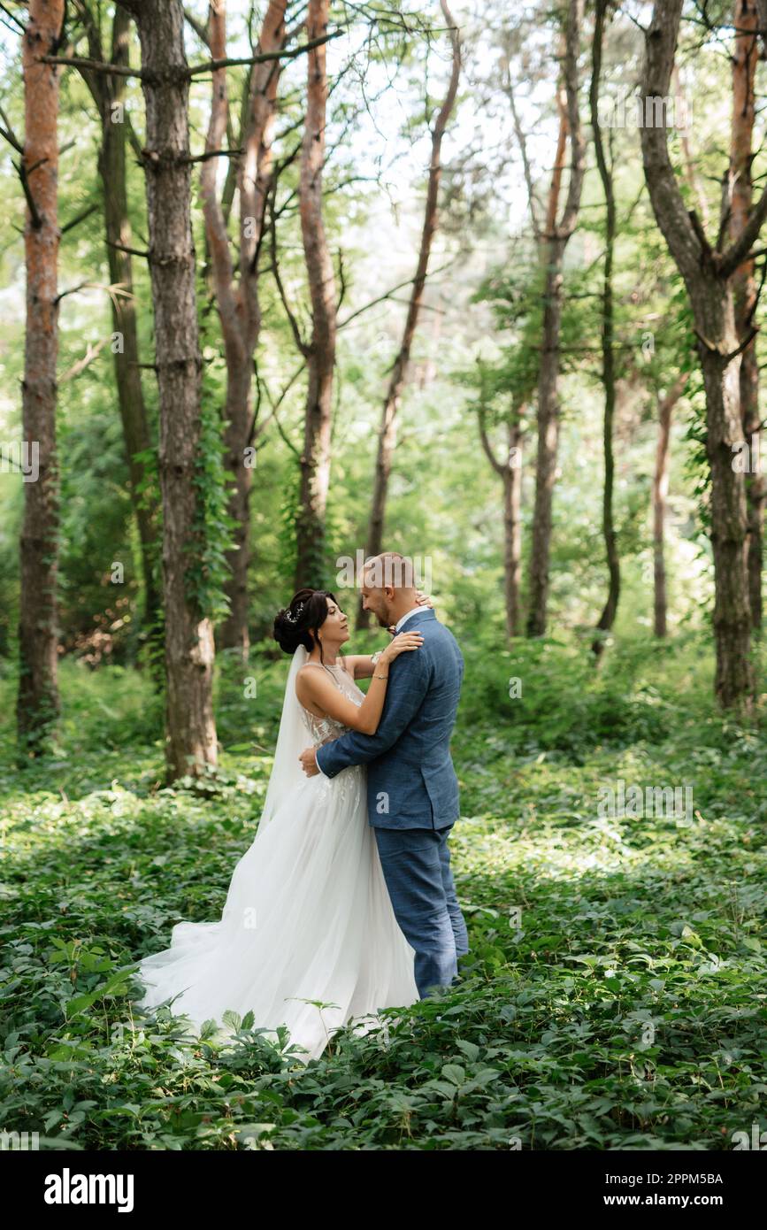 wedding walk of the bride and groom in the deciduous forest in summer ...