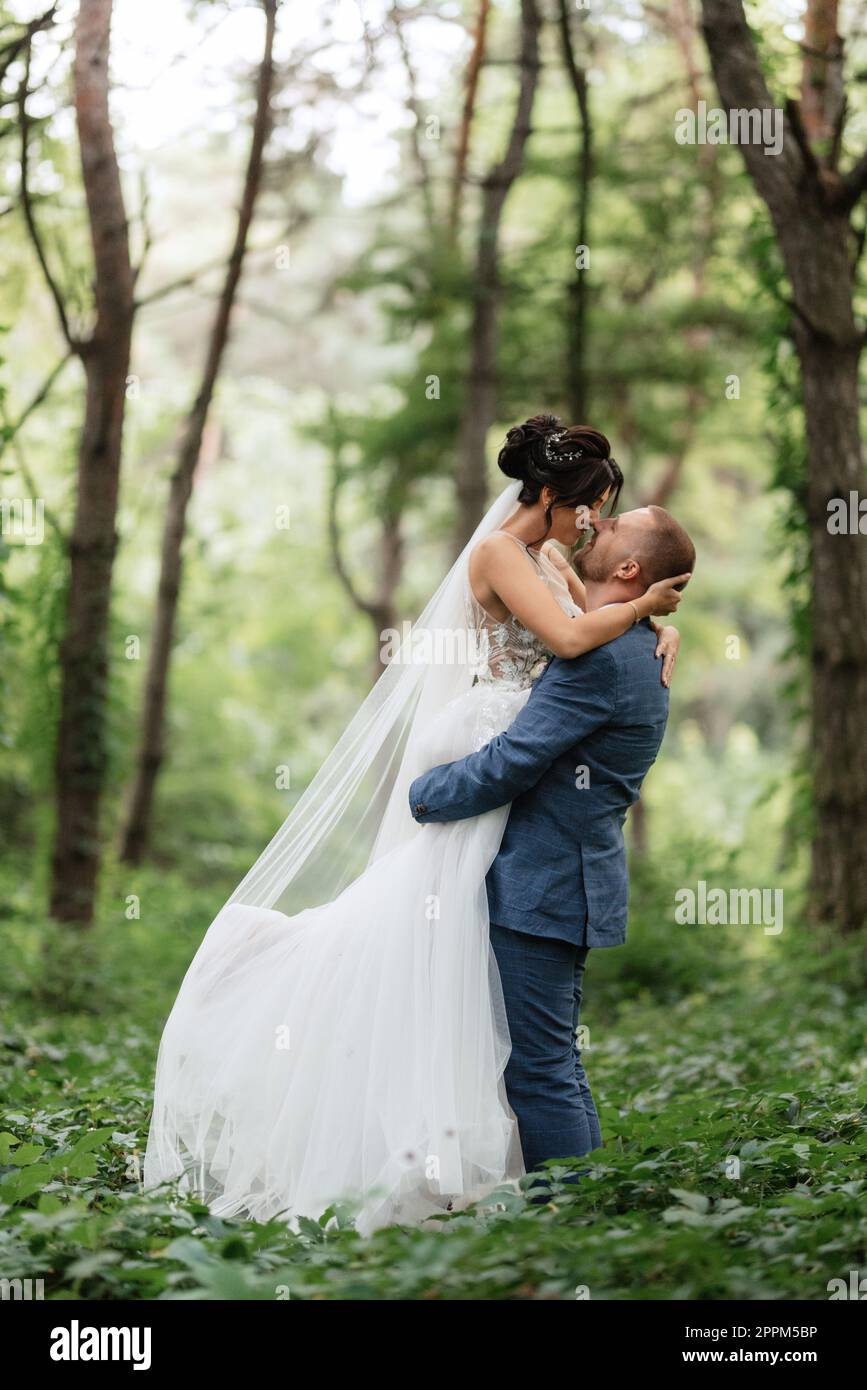 wedding walk of the bride and groom in the deciduous forest in summer ...