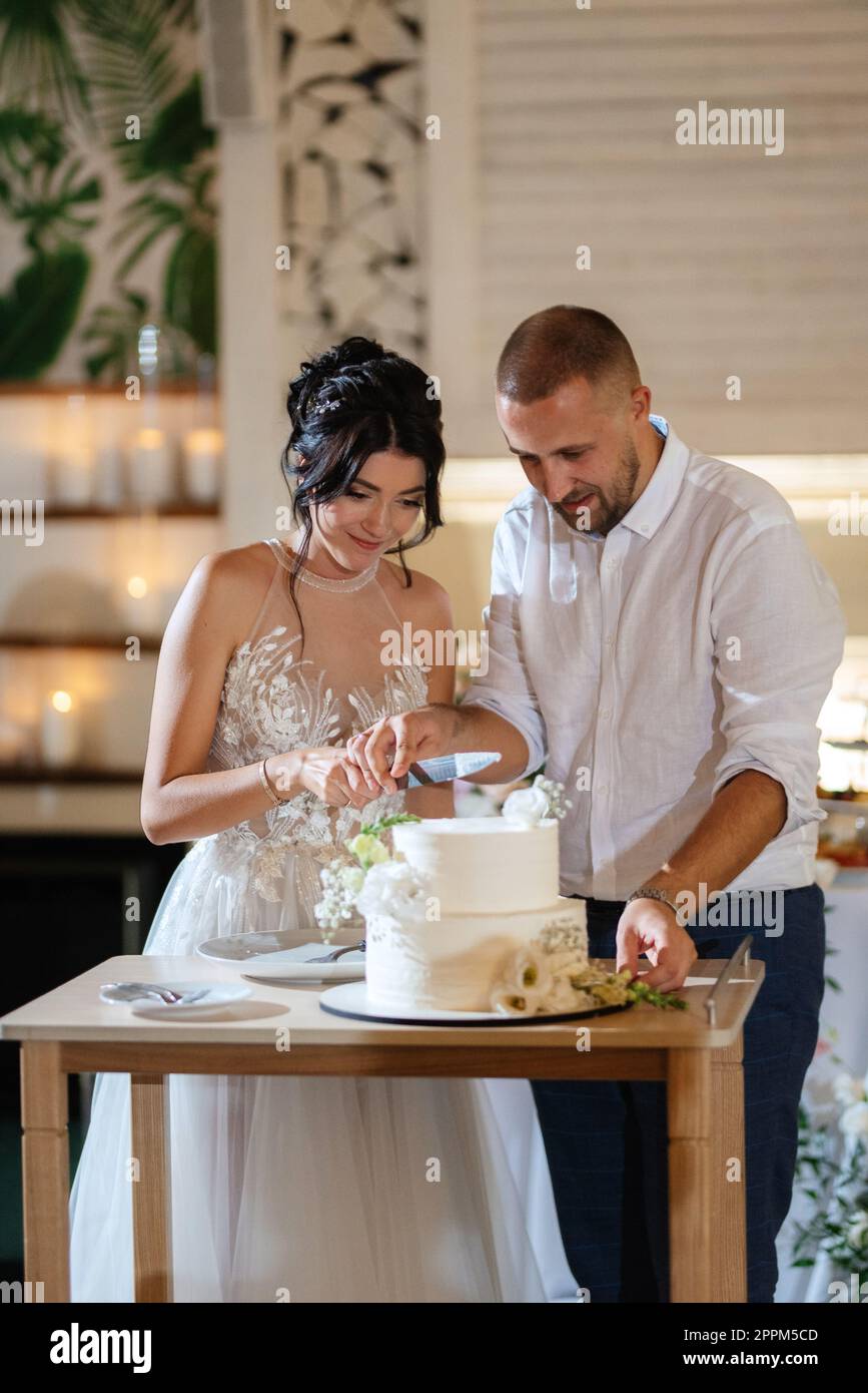 newlyweds happily cut and taste the wedding cake Stock Photo