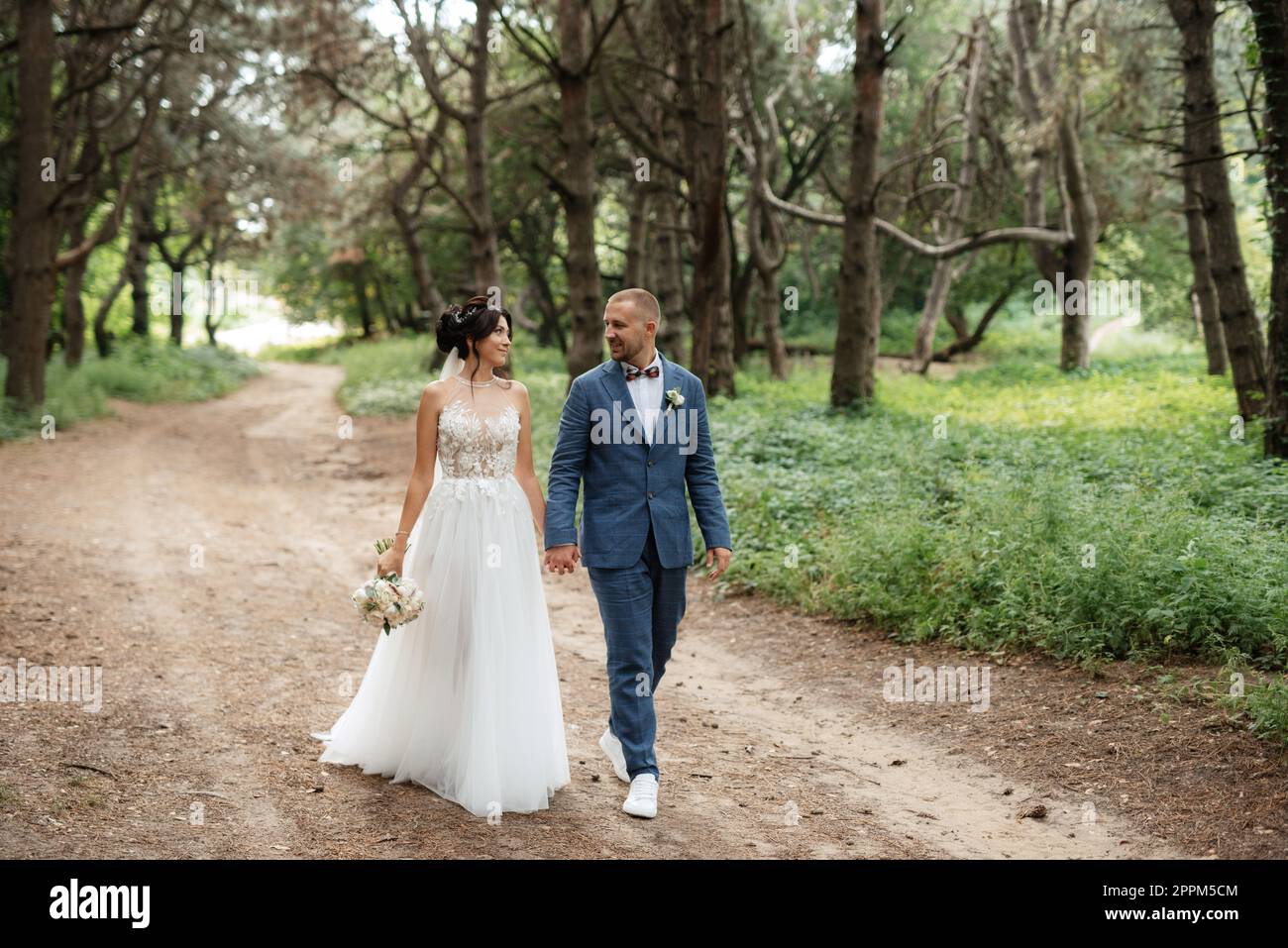 wedding walk of the bride and groom in the deciduous forest in summer Stock Photo