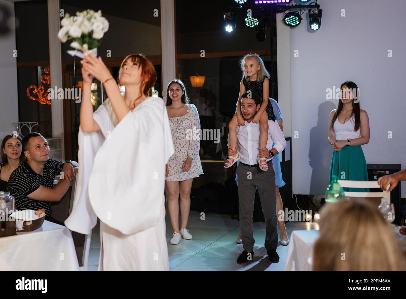 a bride in a white dress throws a wedding bouquet Stock Photo