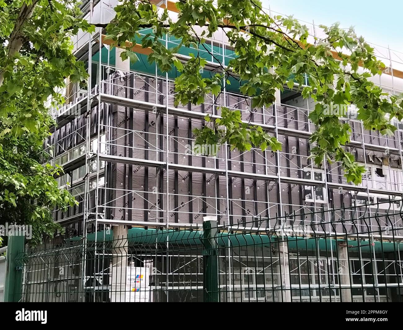 Sremska Mitrovica, Serbia, May 30, 2020. Construction of a new school building. Scaffolding on the facade. Metal fence. Finishing work Stock Photo
