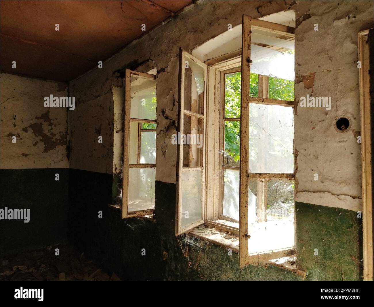 Inside abandoned house. View on broken windows without curtain. Grunge scene. Through the old wooden frames with broken glass breaks warm sunlight. The concept of change, abandonment, uselessness. Stock Photo