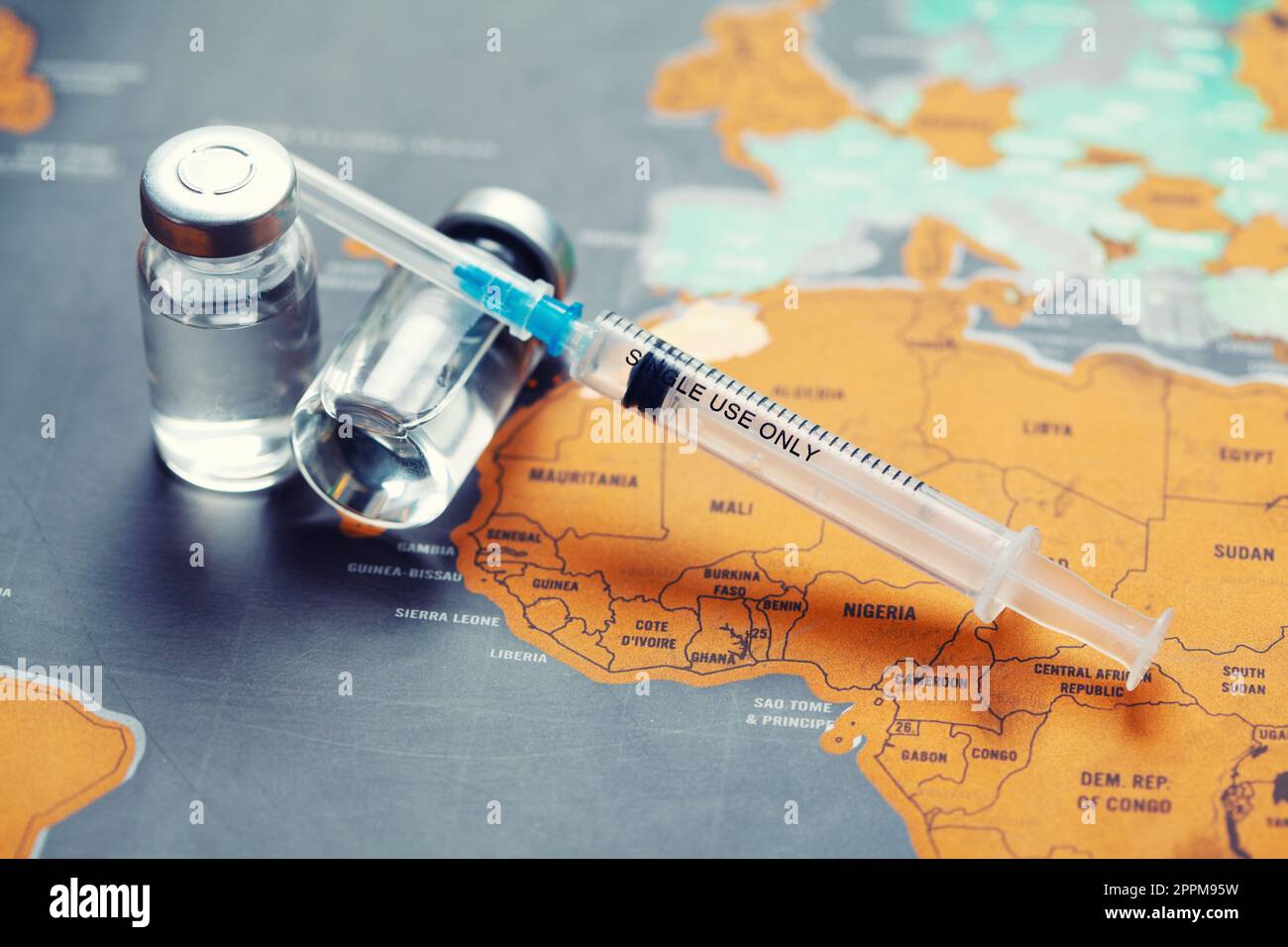 Medical syringe with a needle and a bollte with vaccine on world map. Stock Photo