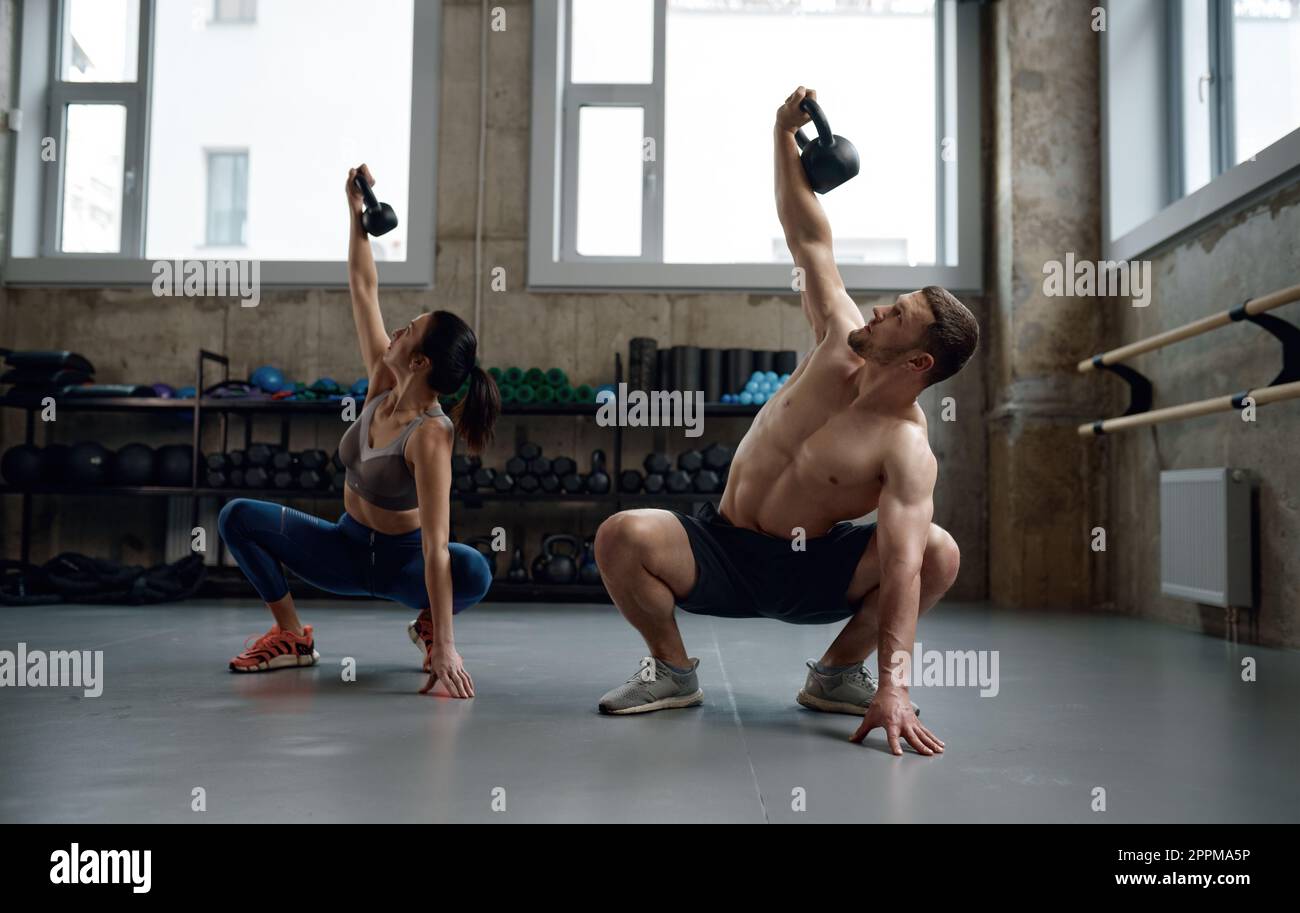 Man and woman with good physique holding heavy kettle bell Stock Photo