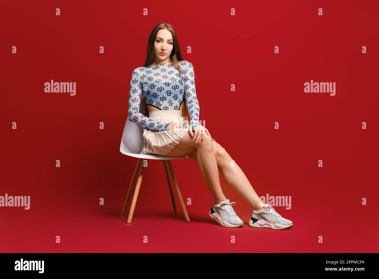 Self-confident sporty woman sitting on a chair in red studio Stock Photo