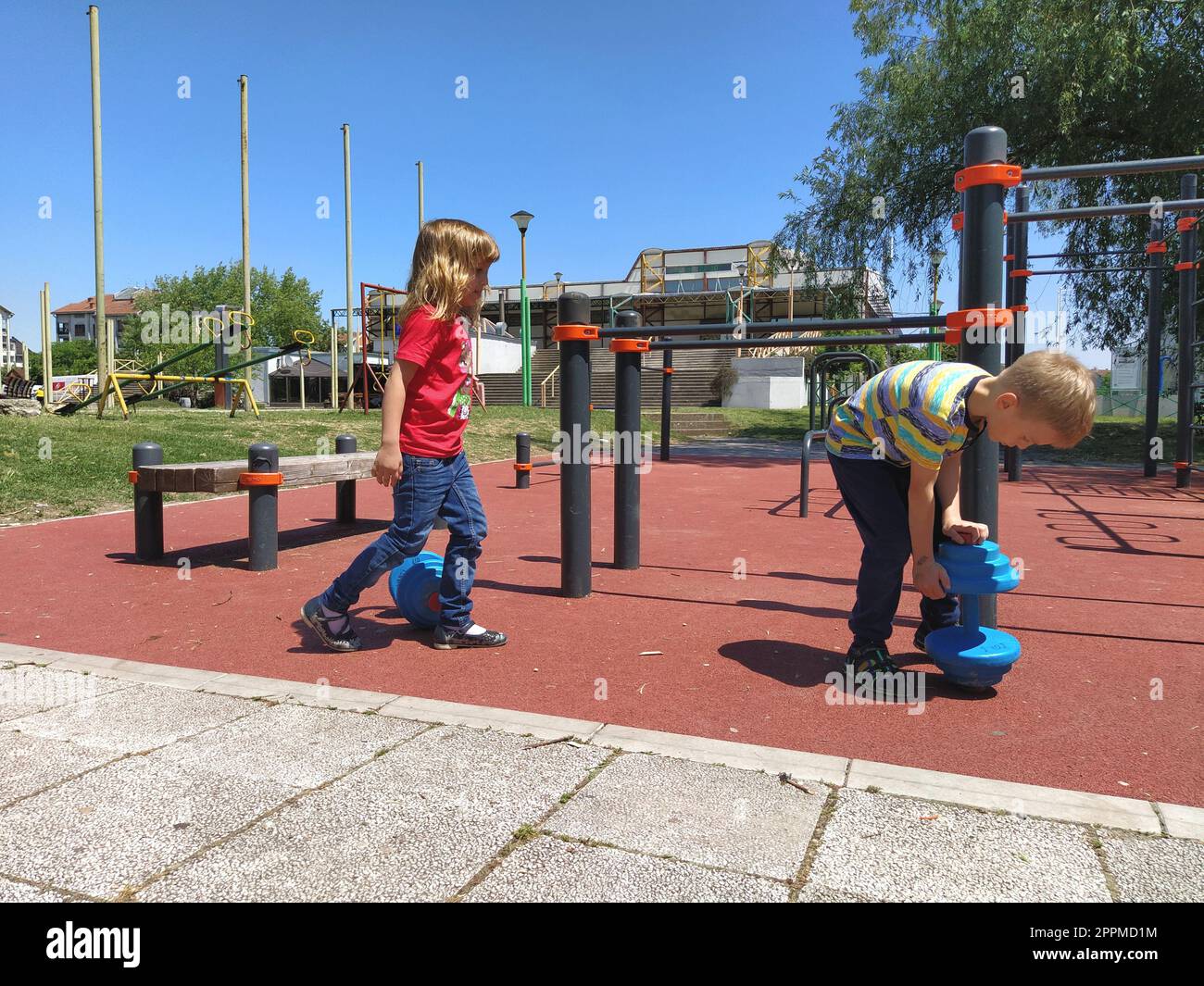 Sremska Mitrovica, Serbia. June 6, 2020. Flip-flops, weight lifting and weights, strength exercises. Two teenagers go in for sports on simulators, children on a sports ground Stock Photo