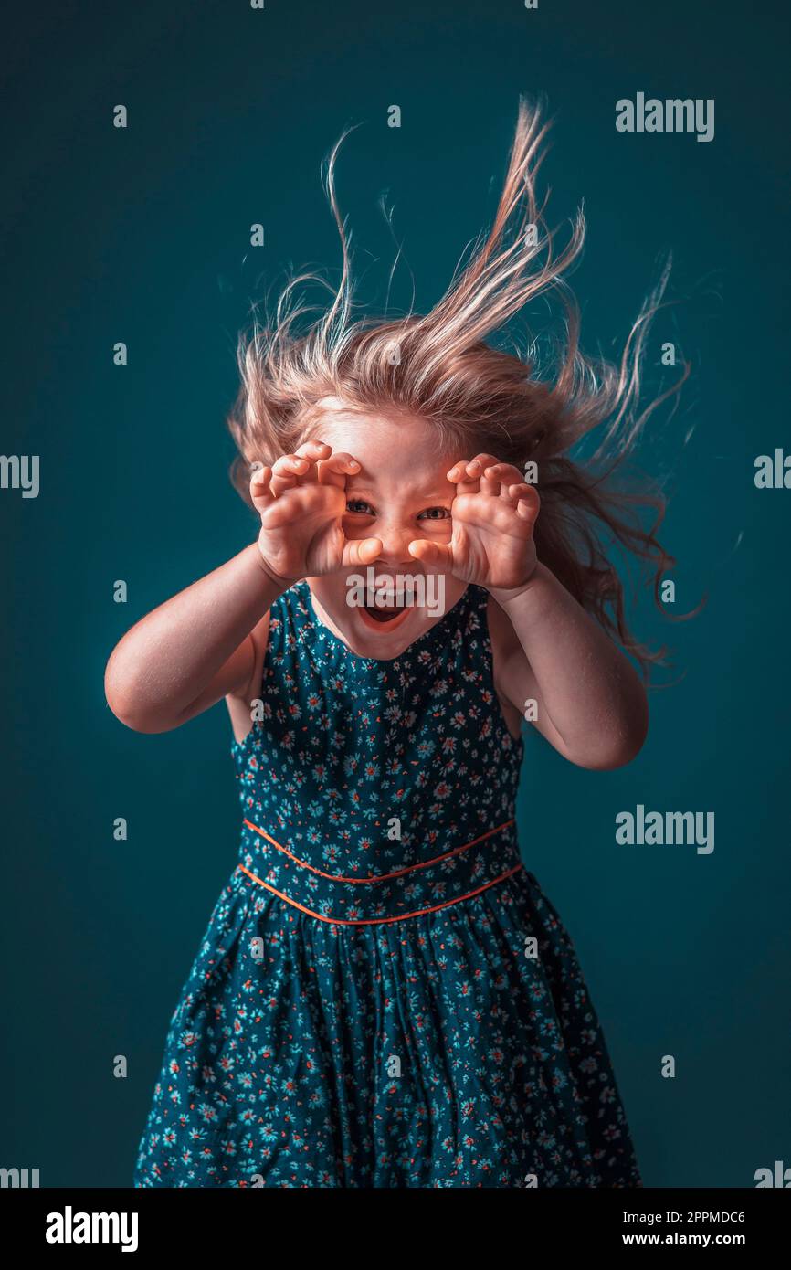 Blonde girl in flowery dress performs a scary face Stock Photo