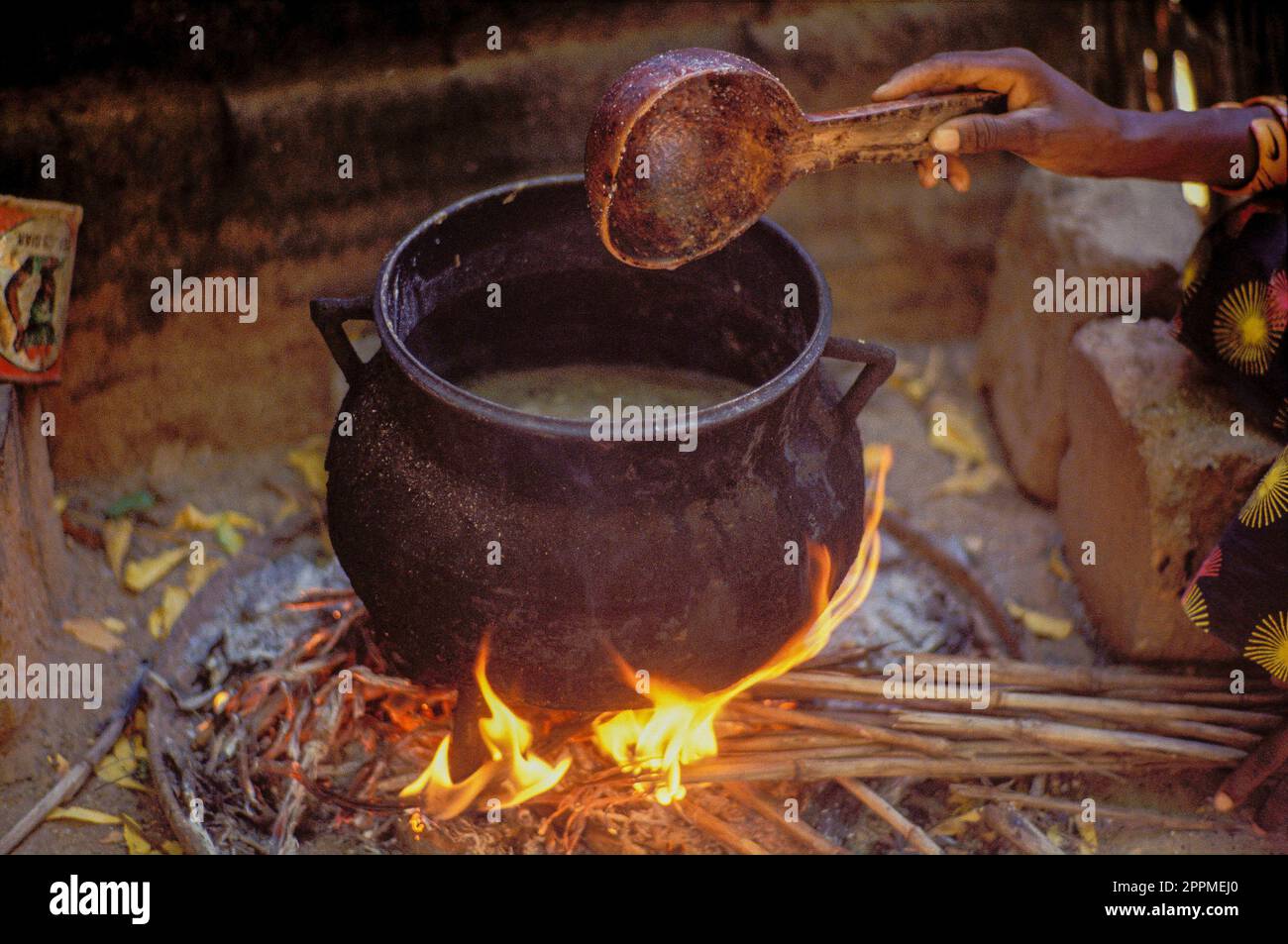 Senegal Woman is cooking in the kitchensite of her hut in the village Kaire. She is using wood as fuel. Woodfire is the common way of cooking the food Stock Photo