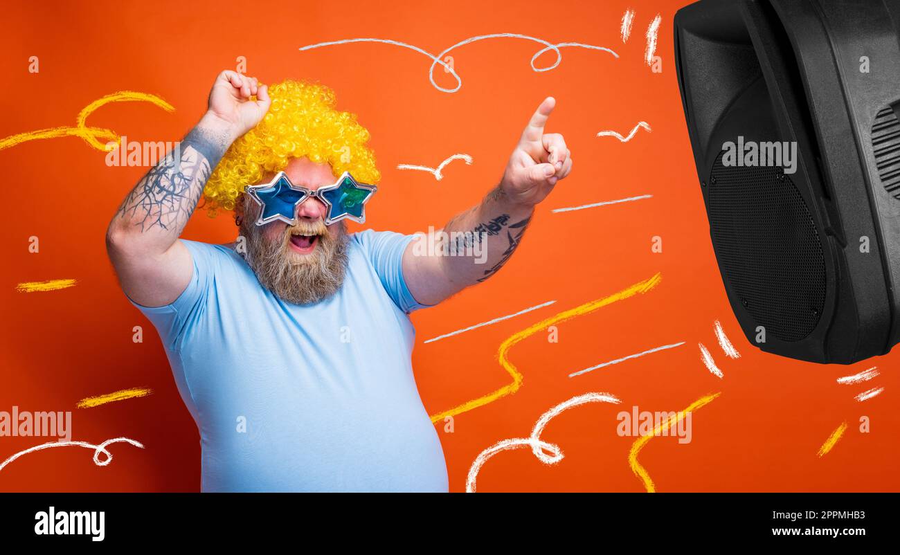 Fat amazed man with beard, tattoos and sunglasses dances music Stock Photo