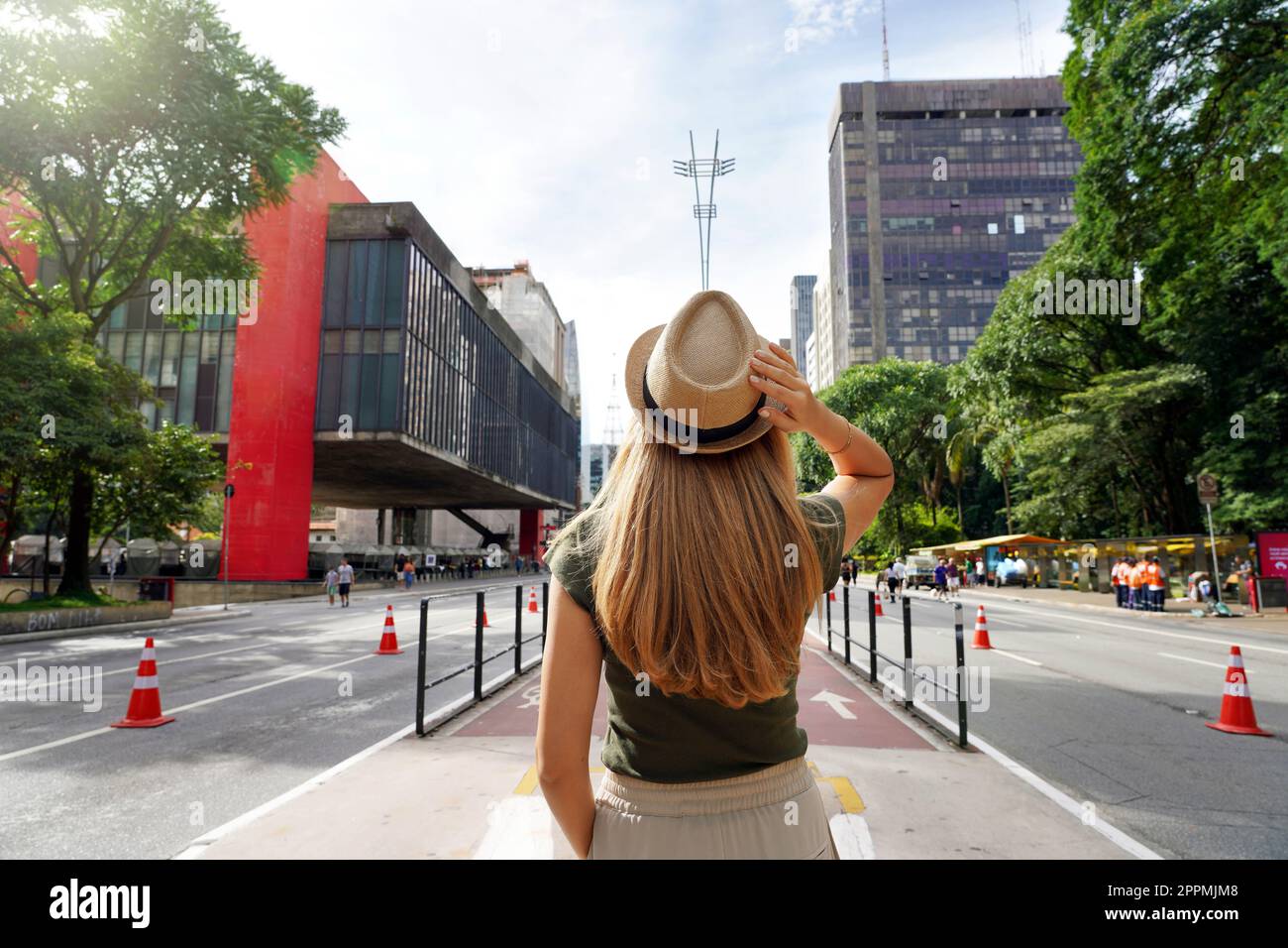 Visiting Sao Paulo City, Brazil. Rear view of beautiful tourist woman with hat walking along Paulista Avenue, Sao Paulo, Brazil. Stock Photo