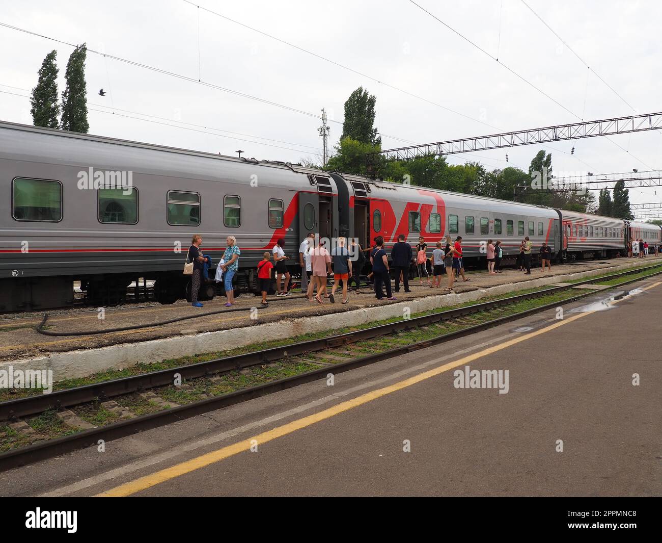 Usman, Lipetsk region, Russia, August 7, 2021. Station of the southeastern railway. The platform with people who got off the train. Russian Railways passenger train. Rails and sleepers. Stopover Stock Photo