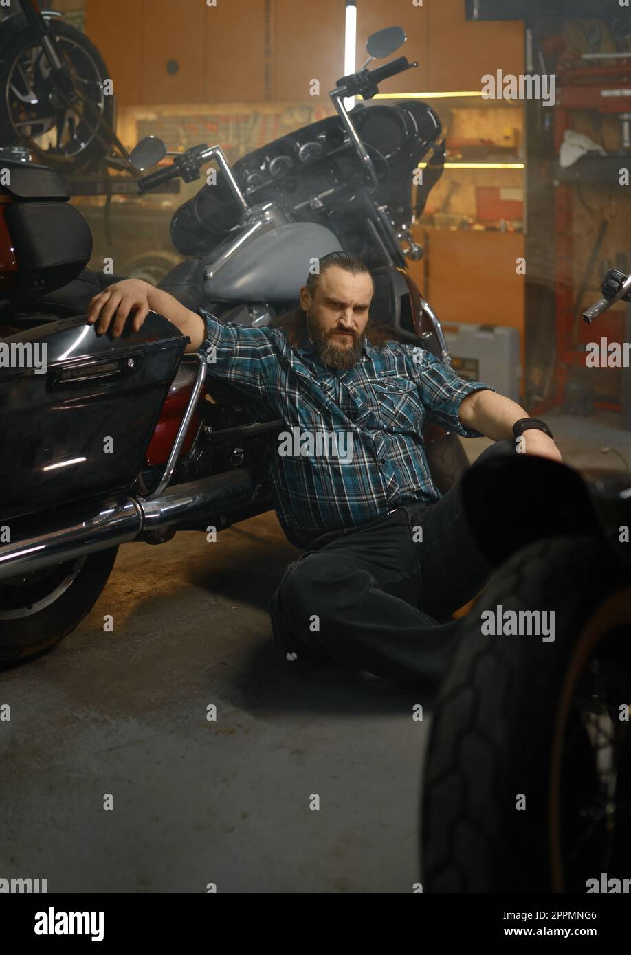 Serious biker sitting on floor and thinking searching way to repair