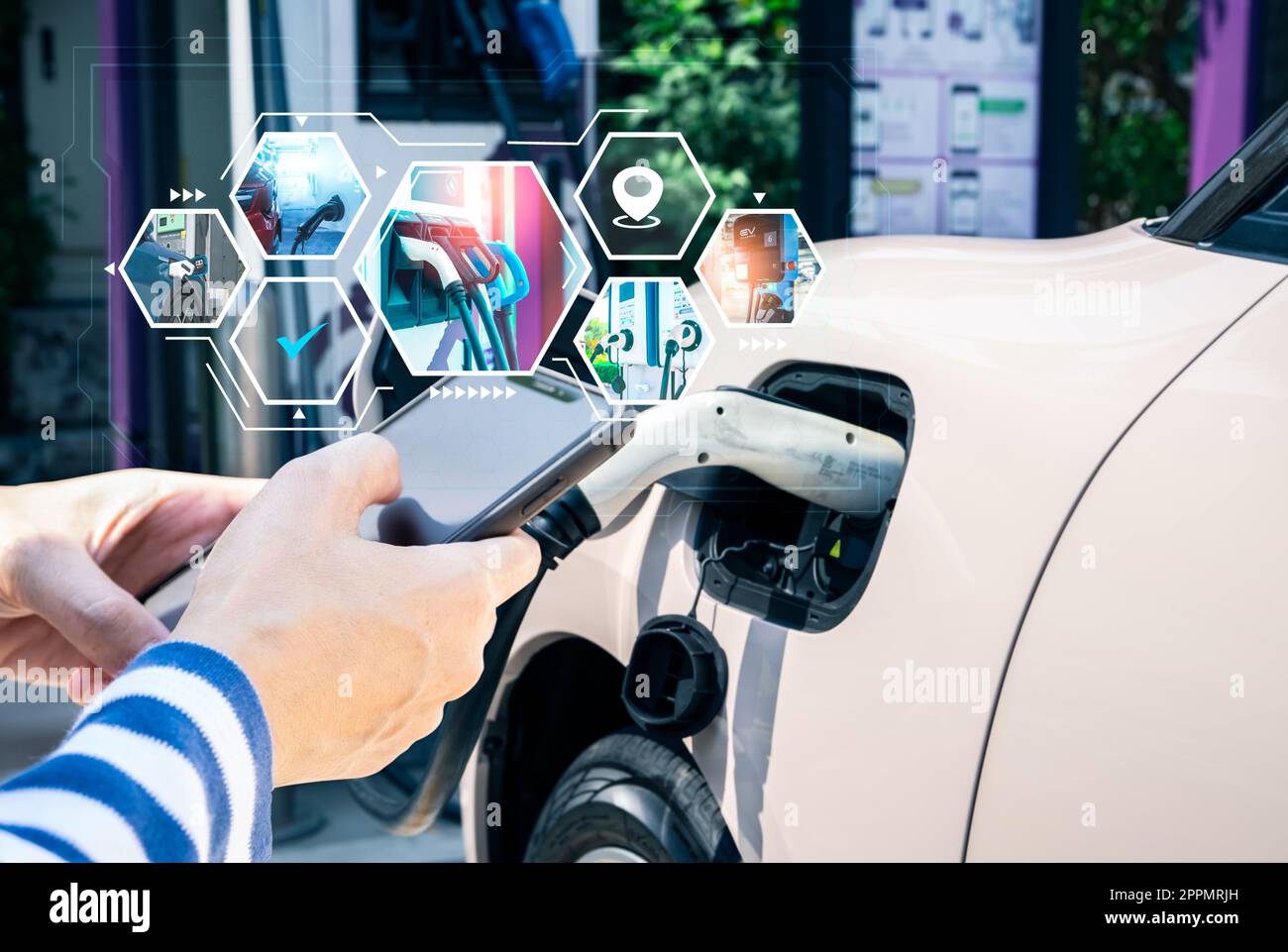 Woman using smartphone paying service in app on blur EV car charging at commercial electric car charging station. EV car charging point. Electric vehicle charging station location. Sustainable power. Stock Photo