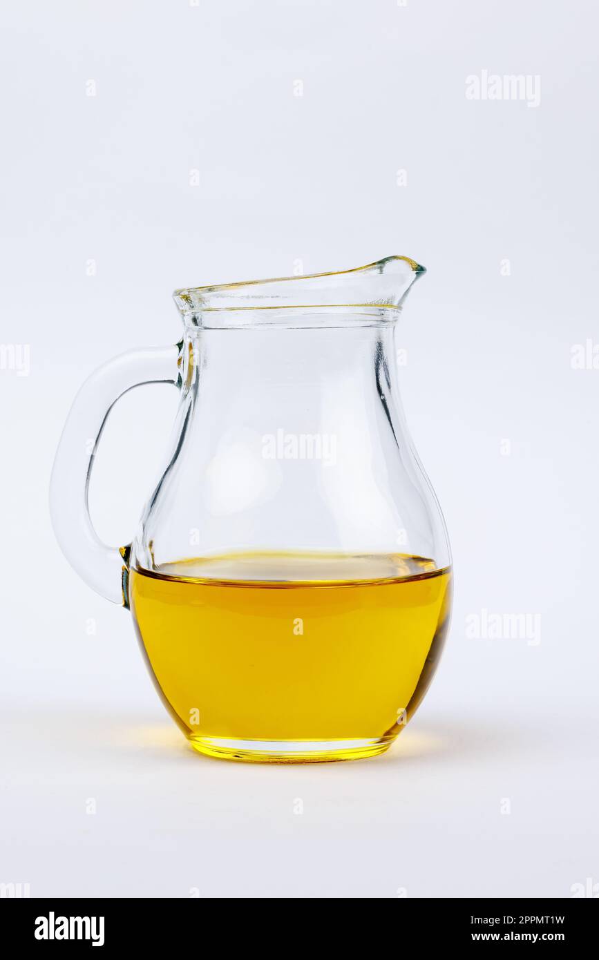 A white ceramic pitcher filled with golden-yellow cooking oil sits on a ...