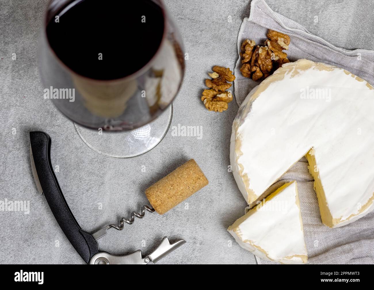 red wine in glass with brie cheese on edge,cork and crowscrew Stock Photo