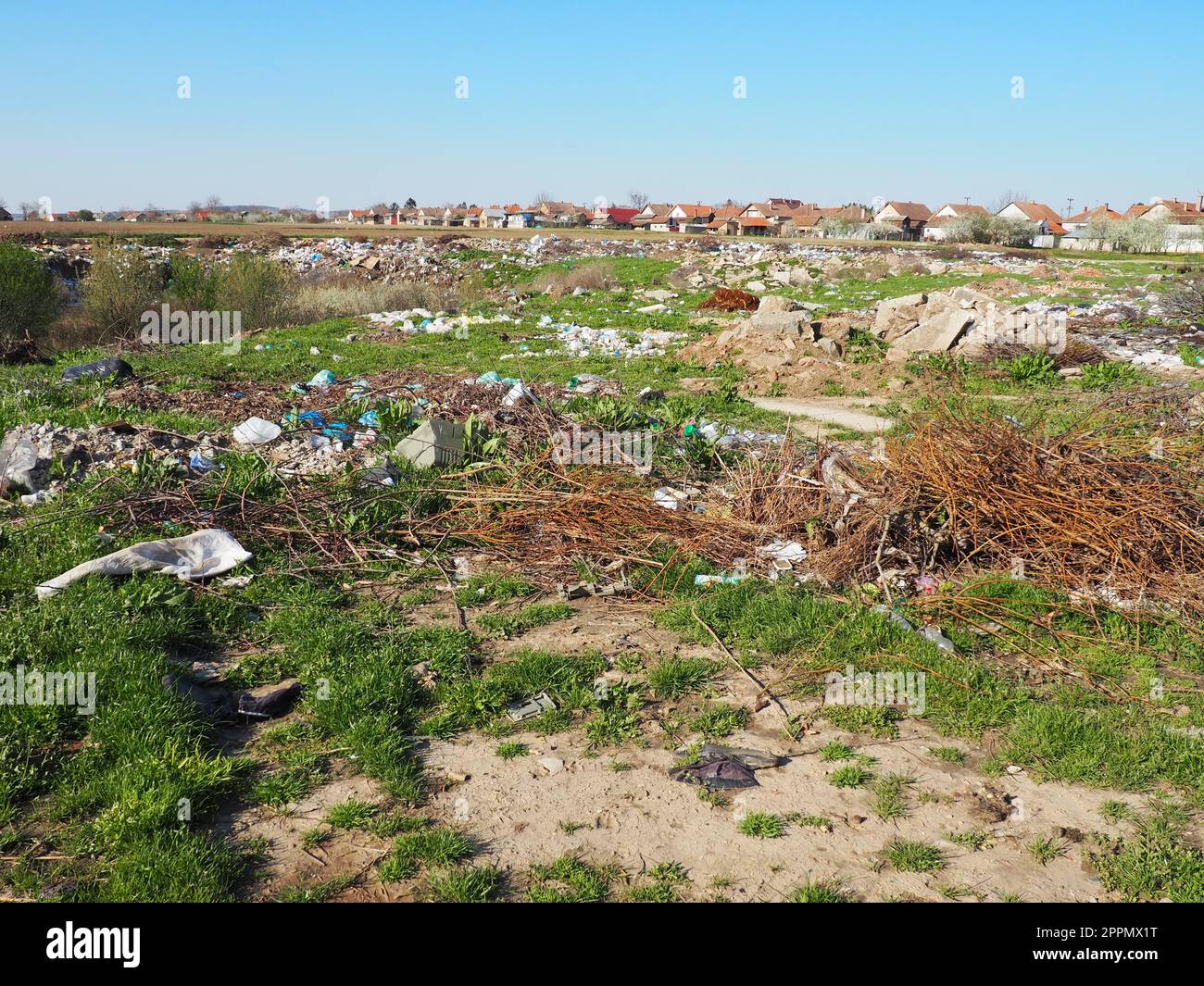 Sremska Mitrovica, Chalma, Serbia, 5 April 2021garbage dump near the village. Chaotic unofficial dump. Plastic, bags, paper, glass, biological waste. Green grass next to dirt. Ecological catastrophy. Stock Photo