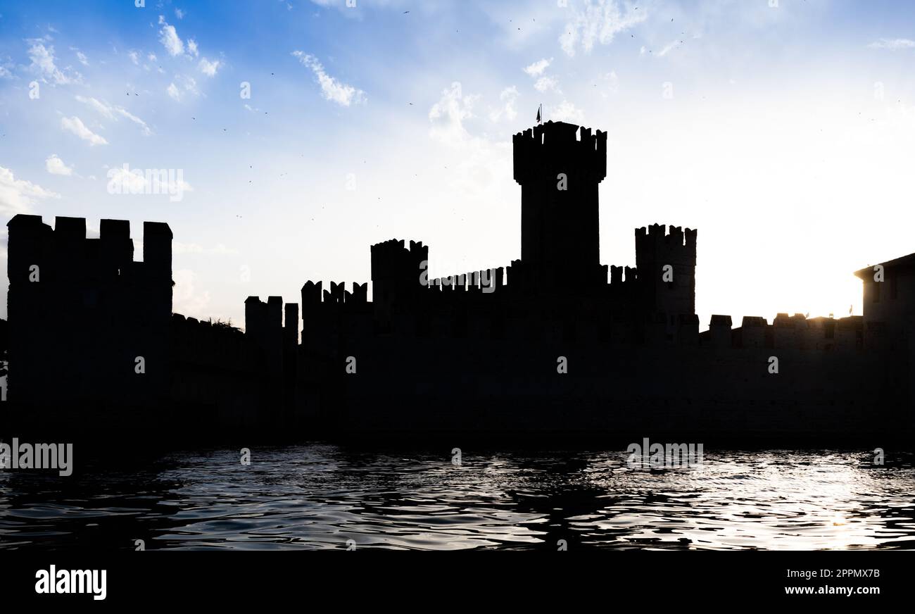Italy - Sirmone castle silhouette on the Garda lake at sunset. Medieval architecture with tower. Stock Photo
