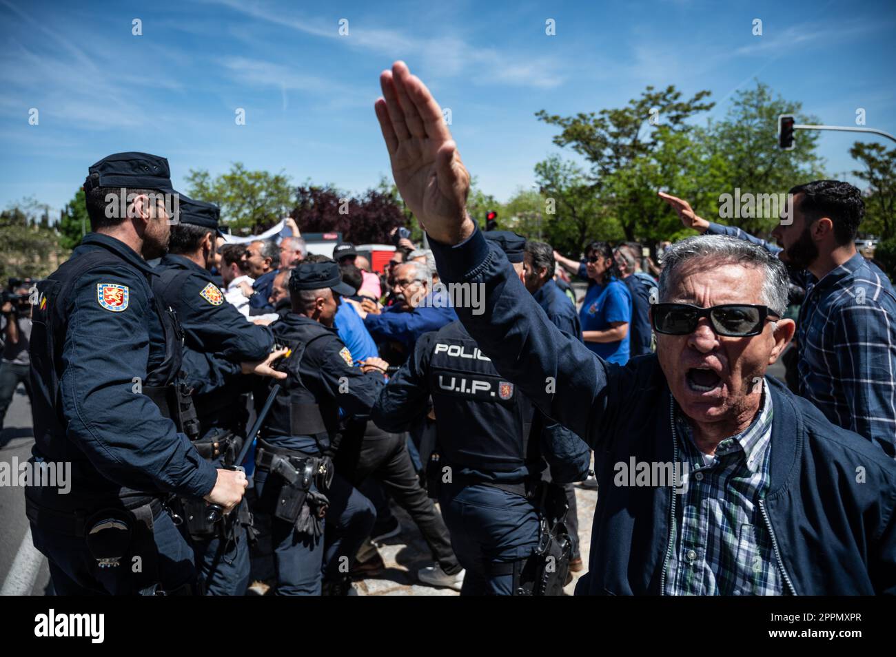 Madrid, Spain. 24th Apr, 2023. Police officers trying to block a group of members and supporters of La Falange party as they raise hands making a fascist salute during a protest outside the San Isidro Cemetery the day of the exhumation of the remains of the founder of Falange, Jose Antonio Primo de Rivera. The fascist politician's remains were exhumed from the Valle de los Caidos (known now as Valle de Cuelgamuros) and transferred to the San Isidro cemetery. Credit: Marcos del Mazo/Alamy Live News Stock Photo