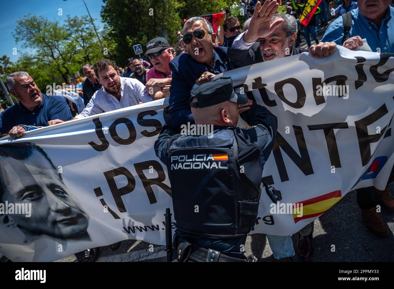 Madrid, Spain. 24th Apr, 2023. A police officer trying to block a group of members and supporters of La Falange party during a protest outside the San Isidro Cemetery the day of the exhumation of the remains of the founder of Falange, Jose Antonio Primo de Rivera. The fascist politician's remains were exhumed from the Valle de los Caidos (known now as Valle de Cuelgamuros) and transferred to the San Isidro cemetery. Credit: Marcos del Mazo/Alamy Live News Stock Photo