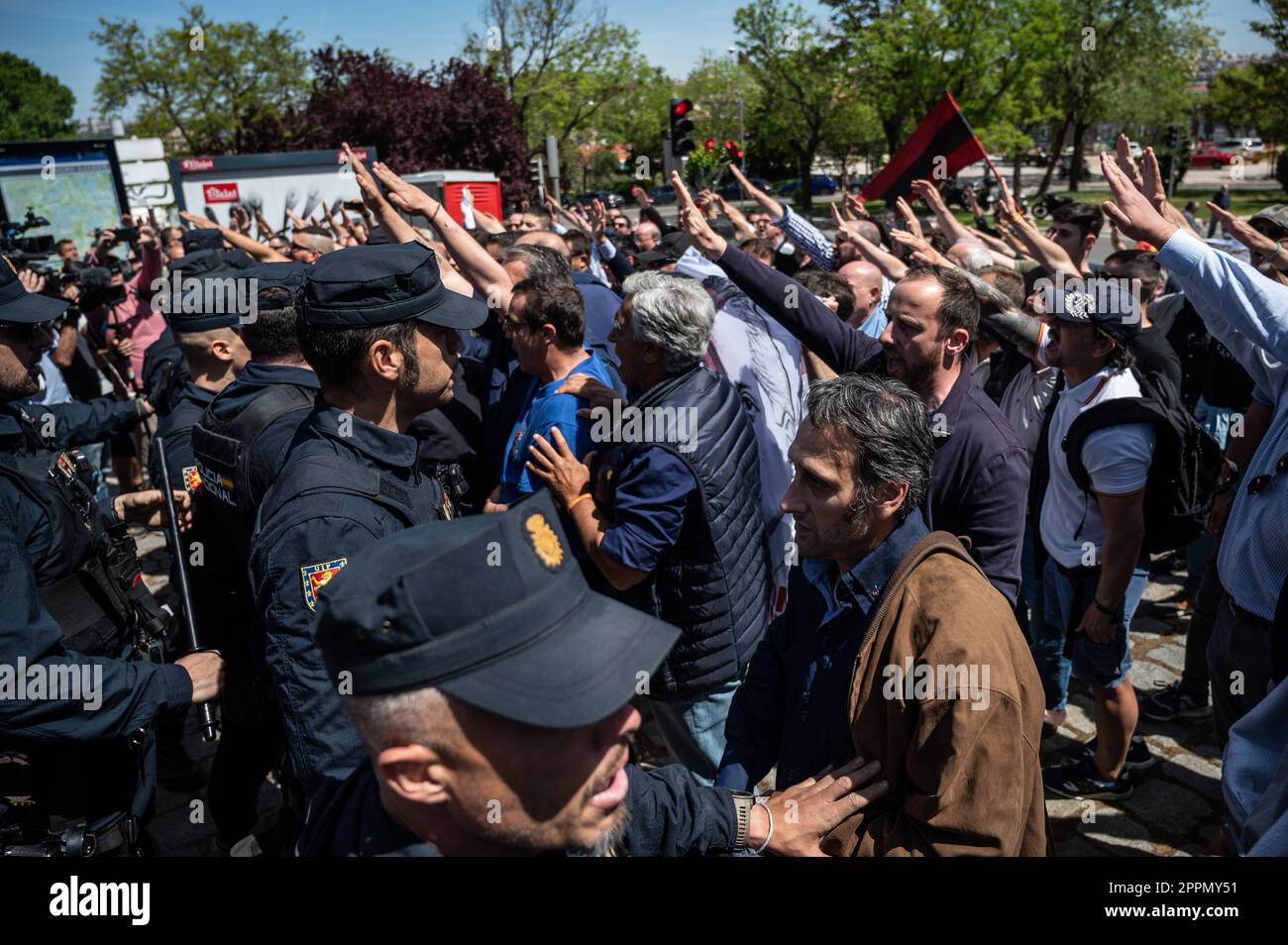 Madrid, Spain. 24th Apr, 2023. Police officers trying to block a group of members and supporters of La Falange party as they raise hands making a fascist salute during a protest outside the San Isidro Cemetery the day of the exhumation of the remains of the founder of Falange, Jose Antonio Primo de Rivera. The fascist politician's remains were exhumed from the Valle de los Caidos (known now as Valle de Cuelgamuros) and transferred to the San Isidro cemetery. Credit: Marcos del Mazo/Alamy Live News Stock Photo