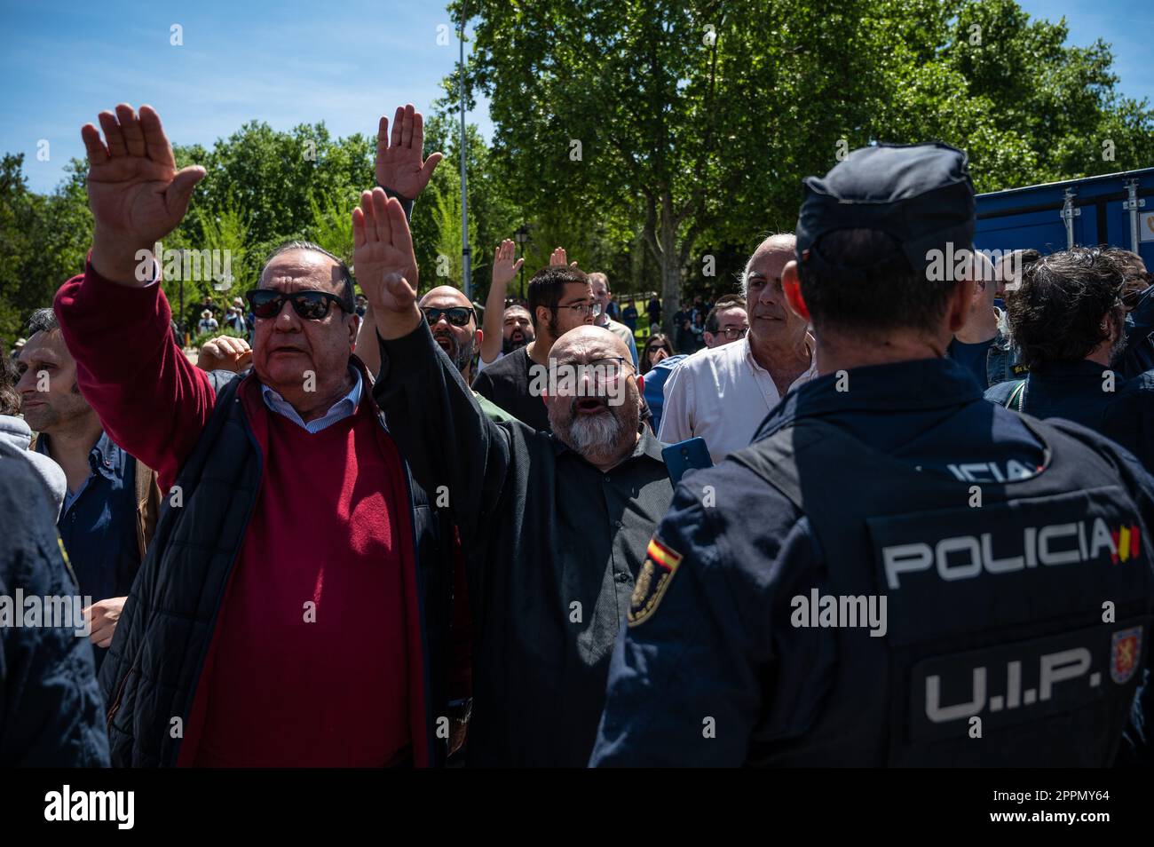 Madrid, Spain. 24th Apr, 2023. Police officers blocking a group of members and supporters of La Falange party as they raise hands making a fascist salute during a protest outside the San Isidro Cemetery the day of the exhumation of the remains of the founder of Falange, Jose Antonio Primo de Rivera. The fascist politician's remains were exhumed from the Valle de los Caidos (known now as Valle de Cuelgamuros) and transferred to the San Isidro cemetery. Credit: Marcos del Mazo/Alamy Live News Stock Photo
