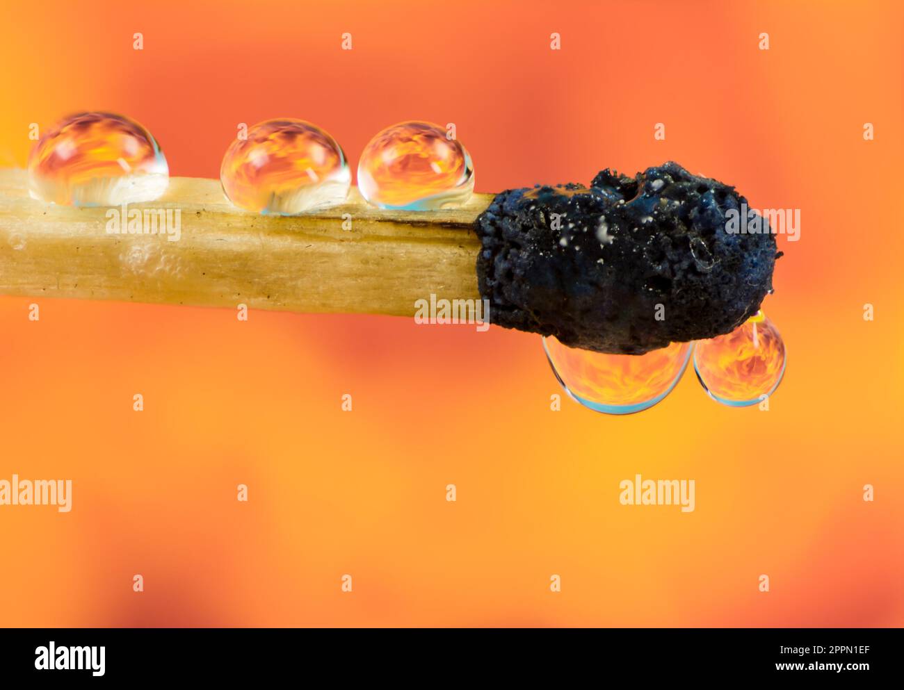 Extinguished Burnt down match with flames of fire refraction in water drops Stock Photo