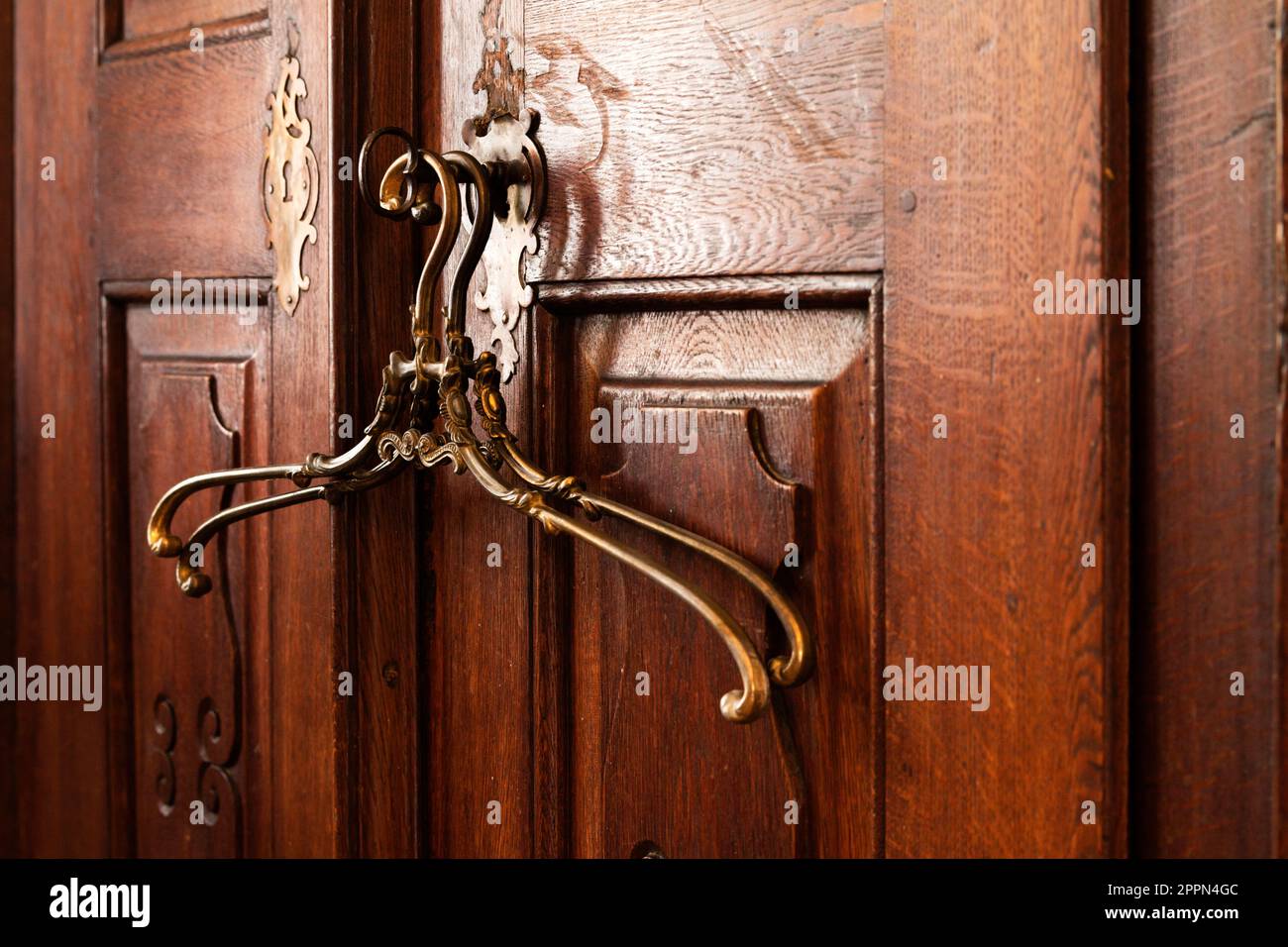 10.08.2021 Miclosoara Romania. Vintage french brass clothes hangers. Old solid wood cabinet. Stock Photo