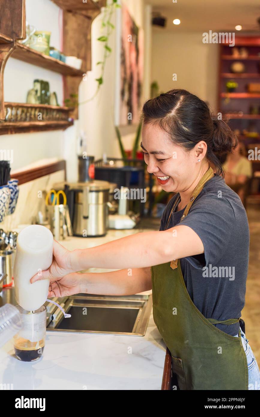 Vietnamese barista pouring condensed milk in glass cup for preparing vietnamese coffee Cafe Sua Stock Photo