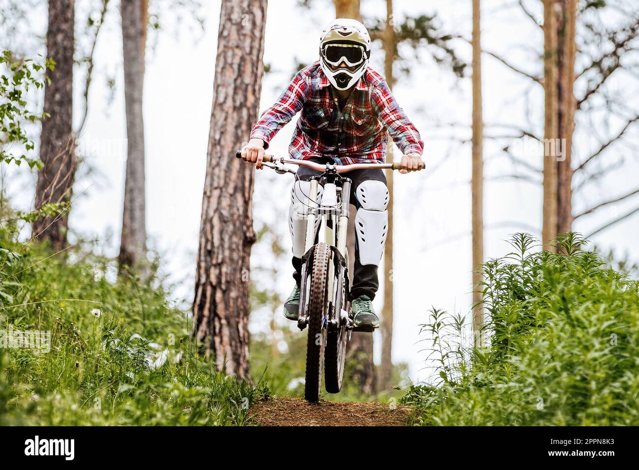 front view racer athlete riding downhill race in mountain bike, on him protection knee and shin