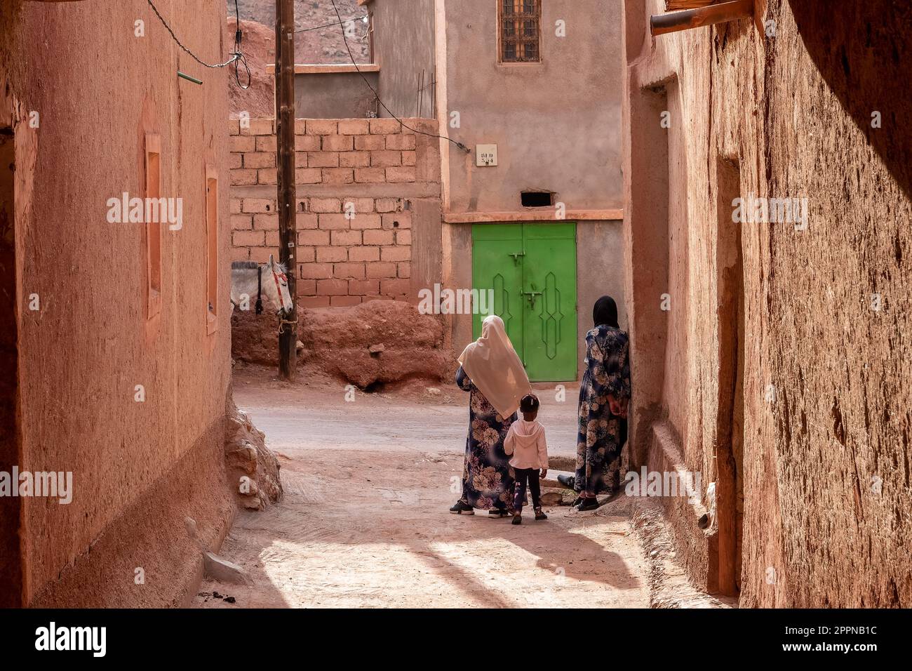 Ansicht eines traditionellen Berberdorfes im Hohen Atlas mit wartenden Frauen in einer Gasse Stock Photo