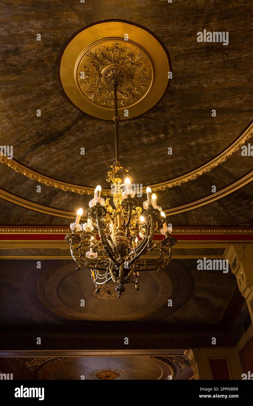 Interior design: richly decorated chandelier under a ceiling with round and gilded stucco elements in the Viennese coffee house Savoy Stock Photo