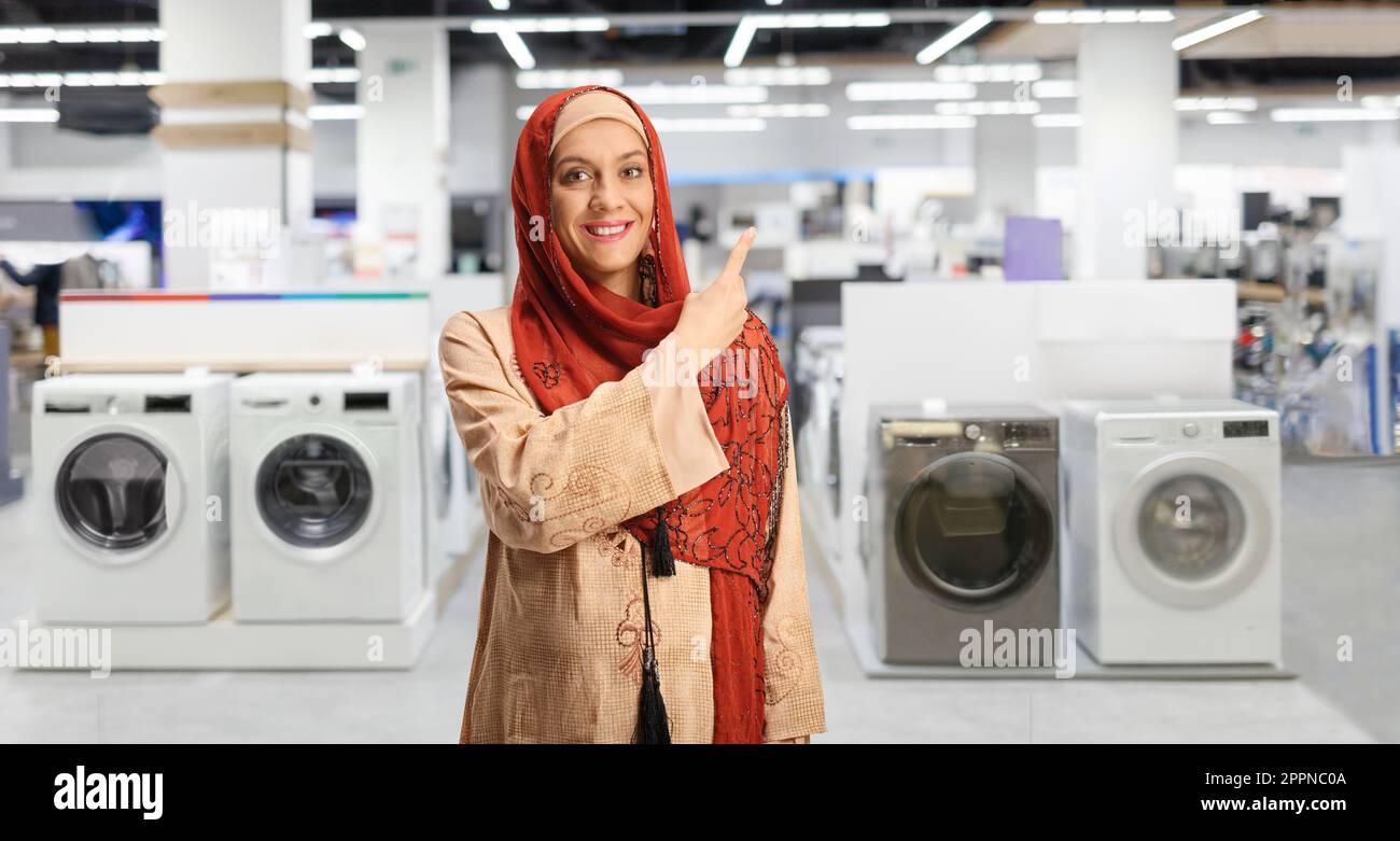 Young arab woman in a hijab pointing at electrical appliances in a store Stock Photo